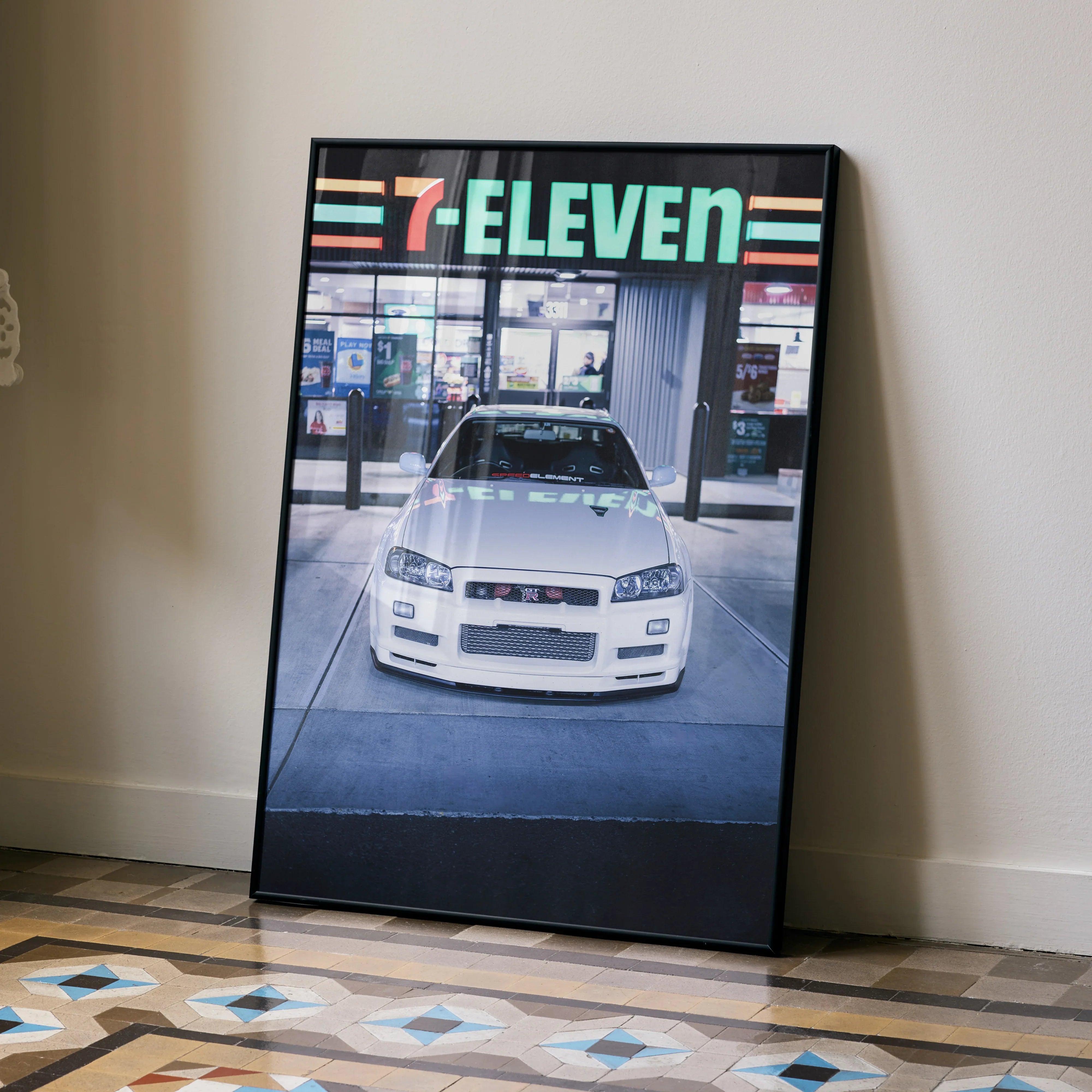 Nissan R34 GTR parked in front of 7-Eleven store poster wall art with urban backdrop.