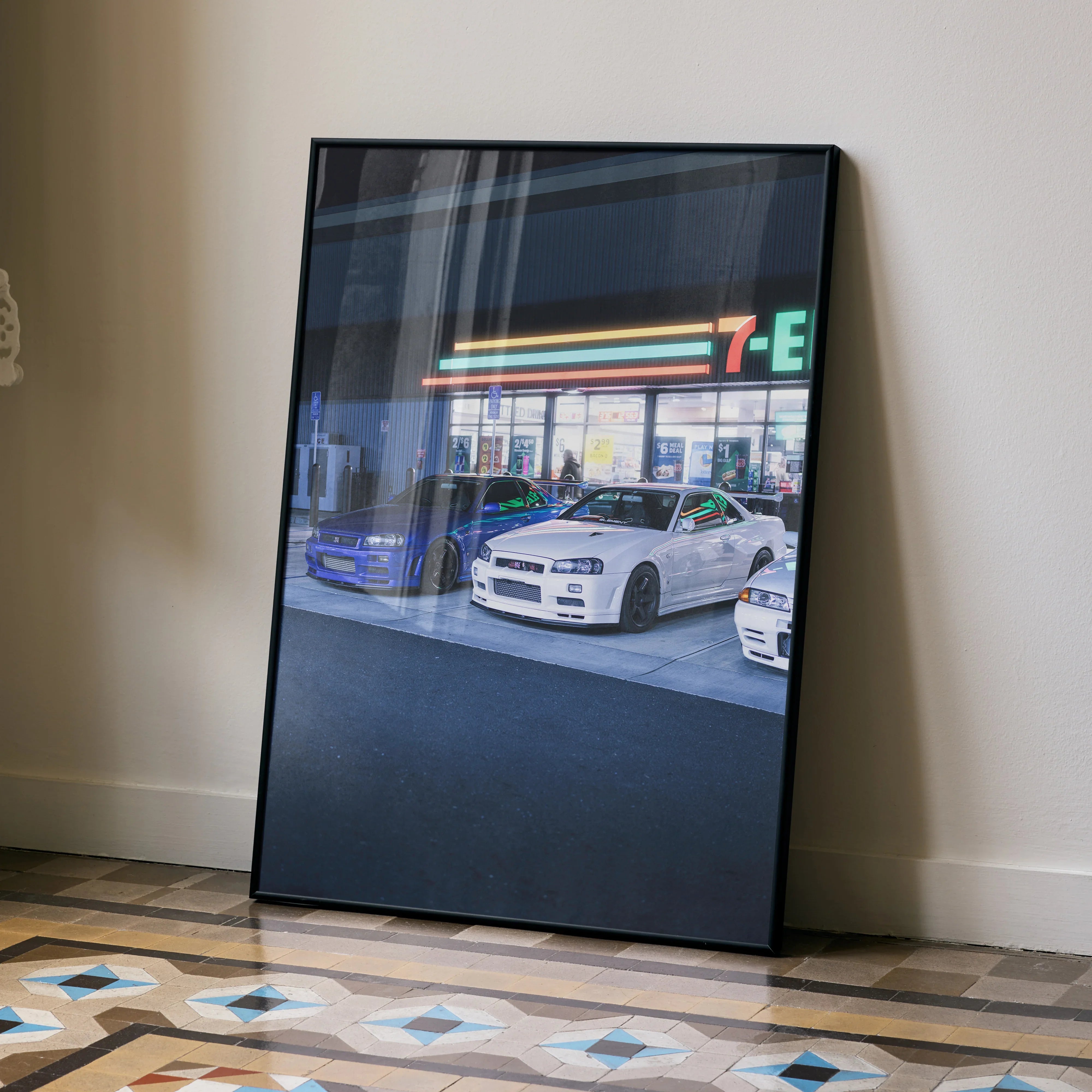 Nissan GTR R34 Skyline parked outside 7-Eleven at night poster wall art in black frame.