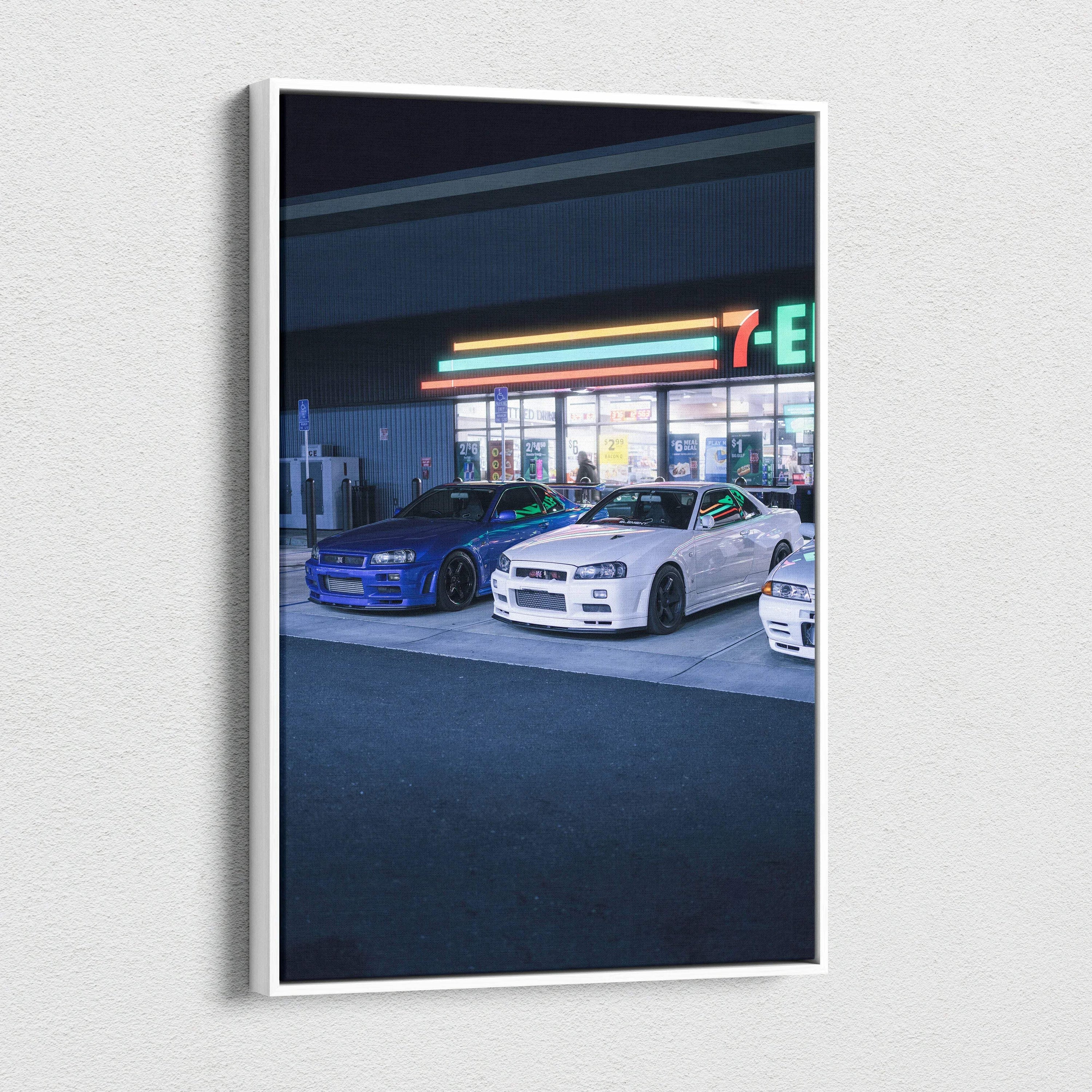 Nissan GTR R34 Skyline canvas art featuring blue and white cars parked in front of a lit convenience store at night,.
