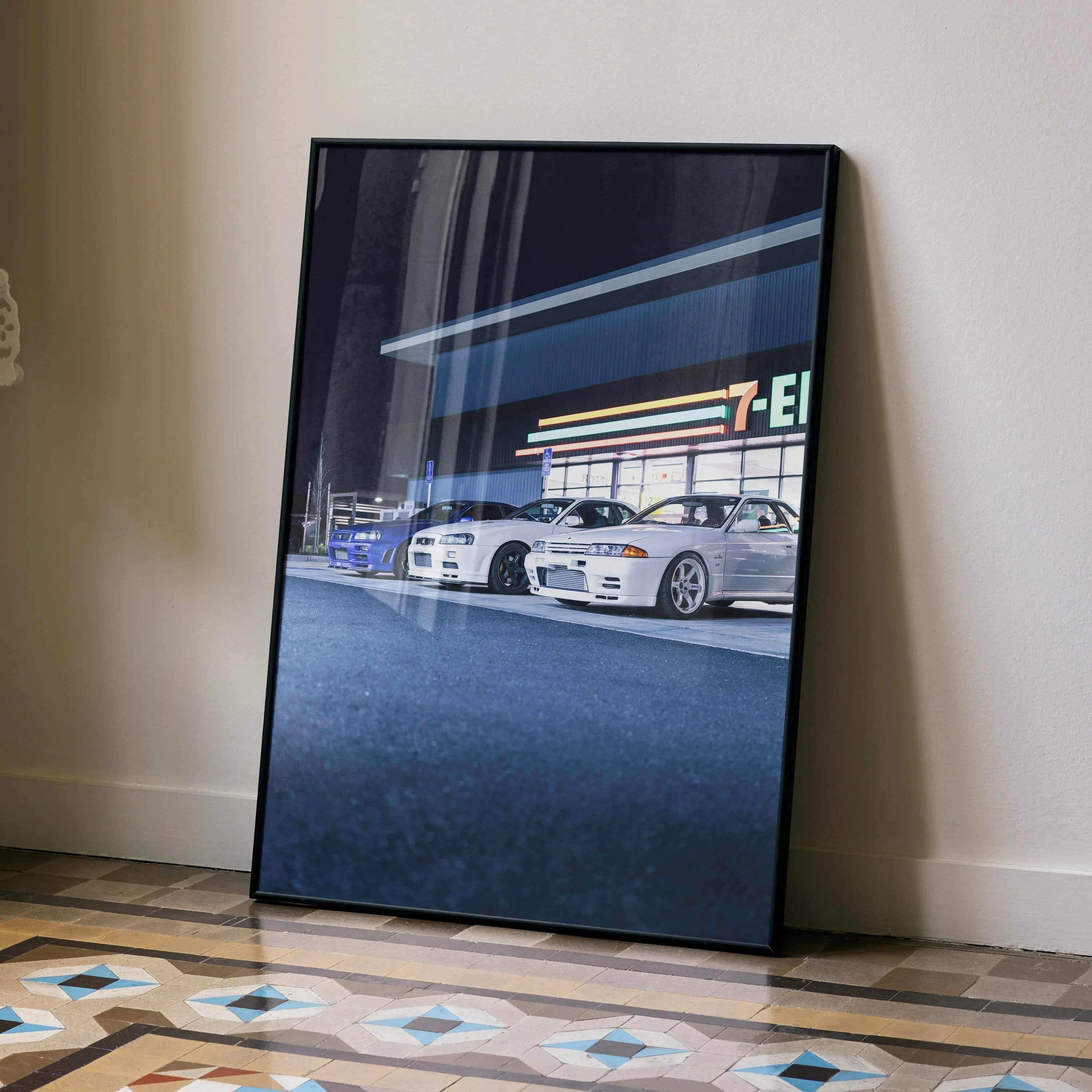 Nissan GTR R32 and R34 Skyline cars in front of a 7-Eleven at night poster wall art in black frame.