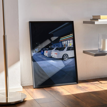 Nissan GTR Skyline poster wall art featuring white R32 and R34 GTRs parked under night lights in a sleek black frame.