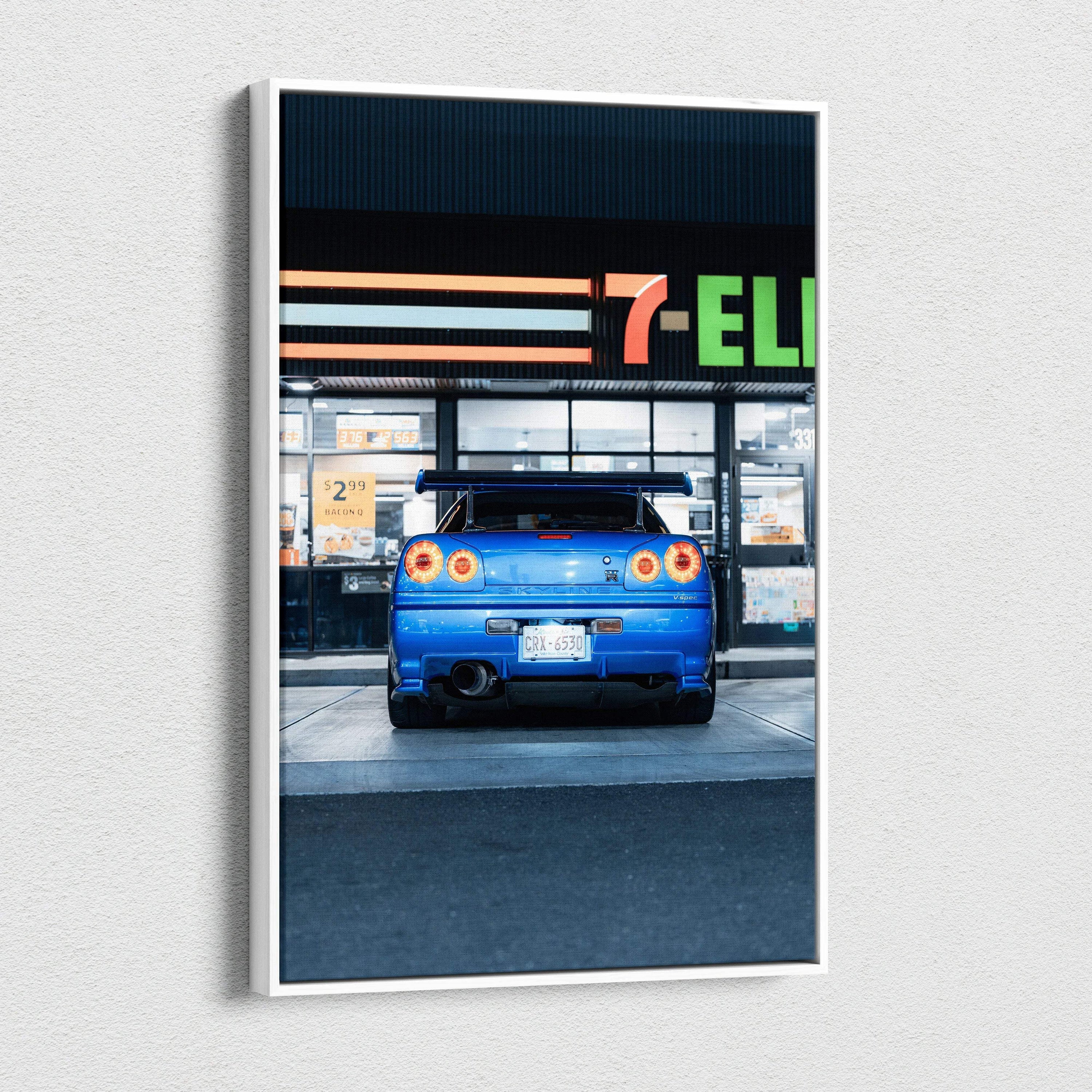 Blue Nissan GTR R34 Skyline rear view on vertical canvas wall art with urban background.
