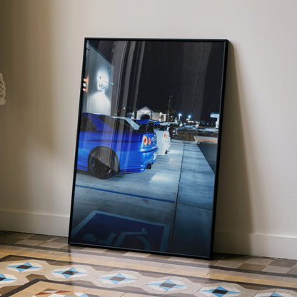 Nissan R34 GTR poster wall art featuring blue car at night with city lights in black frame.