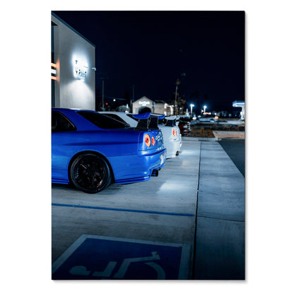 Nissan R34 GTR blue and white parked at night poster wall art with urban background.