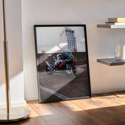 BMW M1000RR motorcycle poster leaning against wall with urban background, framed wall art.