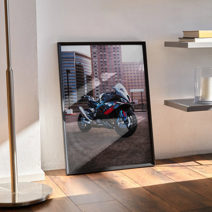 Framed BMW M1000RR motorcycle poster leaning against wall with urban city background wall art print.