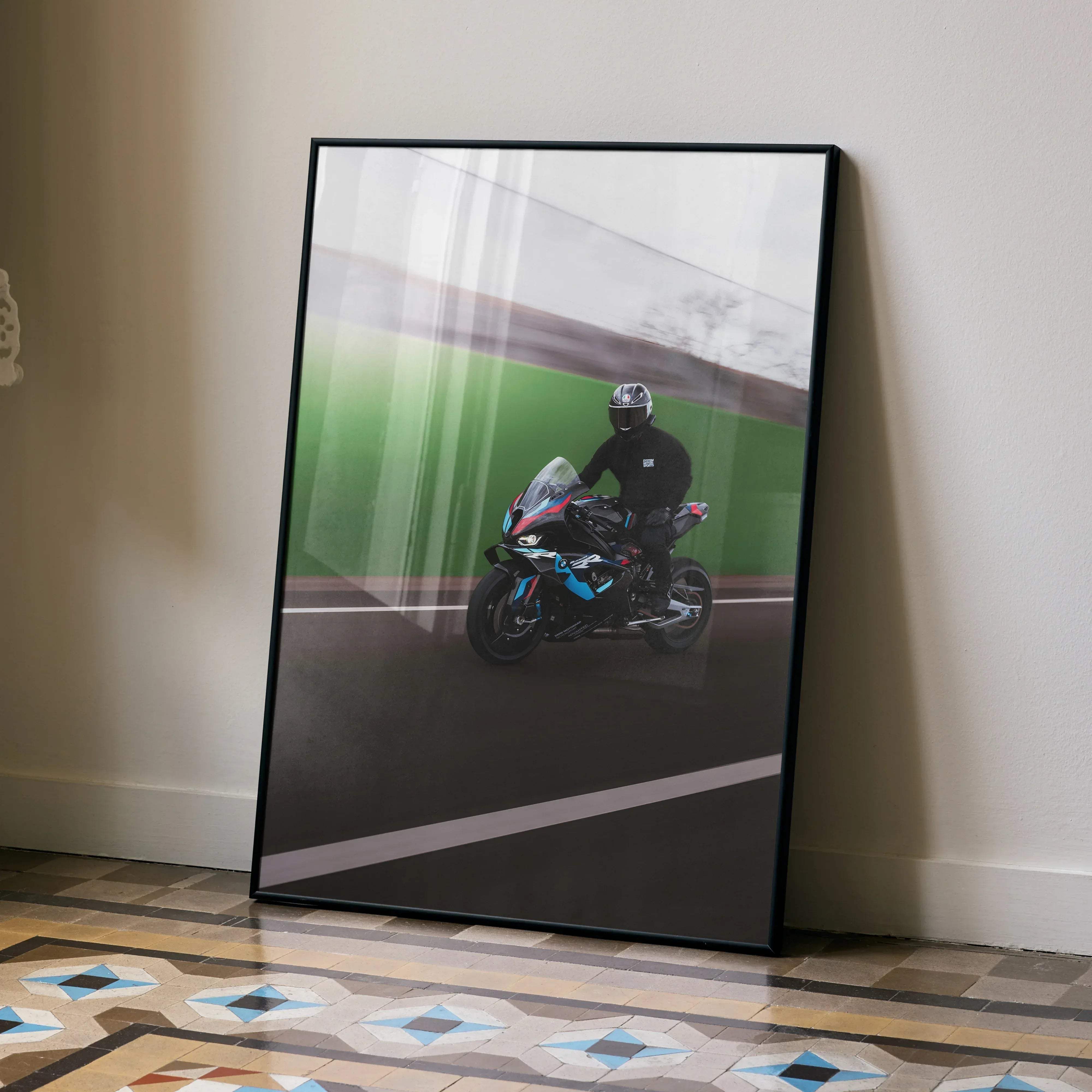 Black-framed biker poster featuring male racer in agv pista helmet on blue and black bmw m1000rr on green track