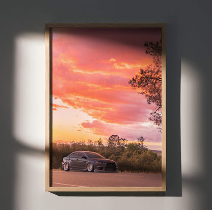 Mitsubishi Evo X parked by shrubbery under vibrant orange and pink sunset sky poster wall art.