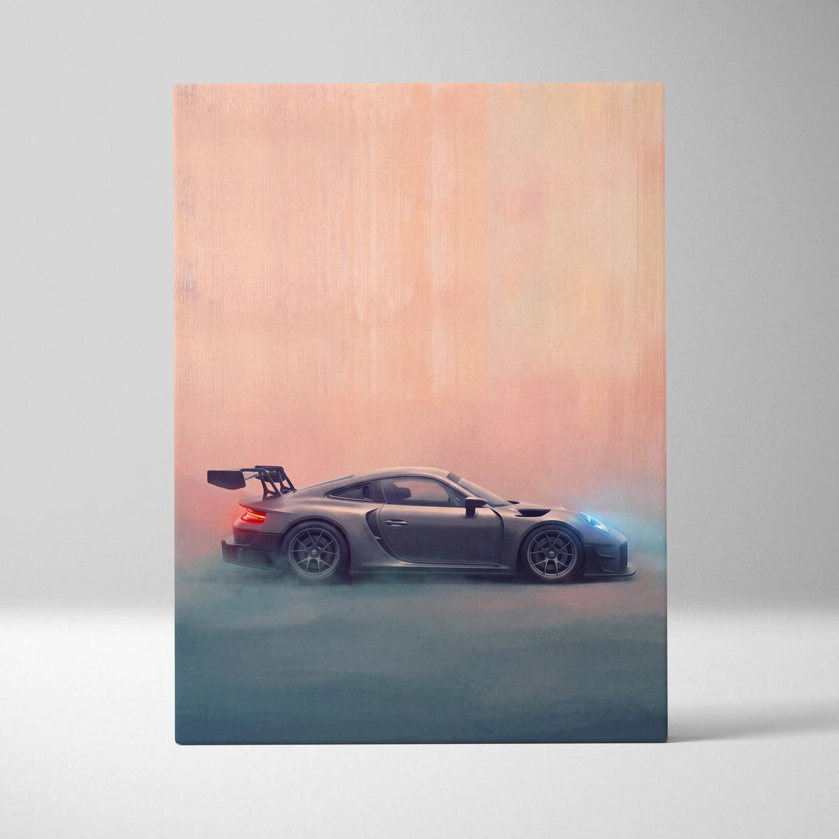 A sleek matte gray porsche 911 gt2 race car with a rear wing in motion on a peach to blue backdrop canvas print