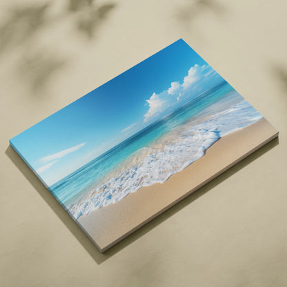Canvas wall art featuring a tranquil beach scene with golden sand, gentle foamy waves, and a bright blue sky with white.