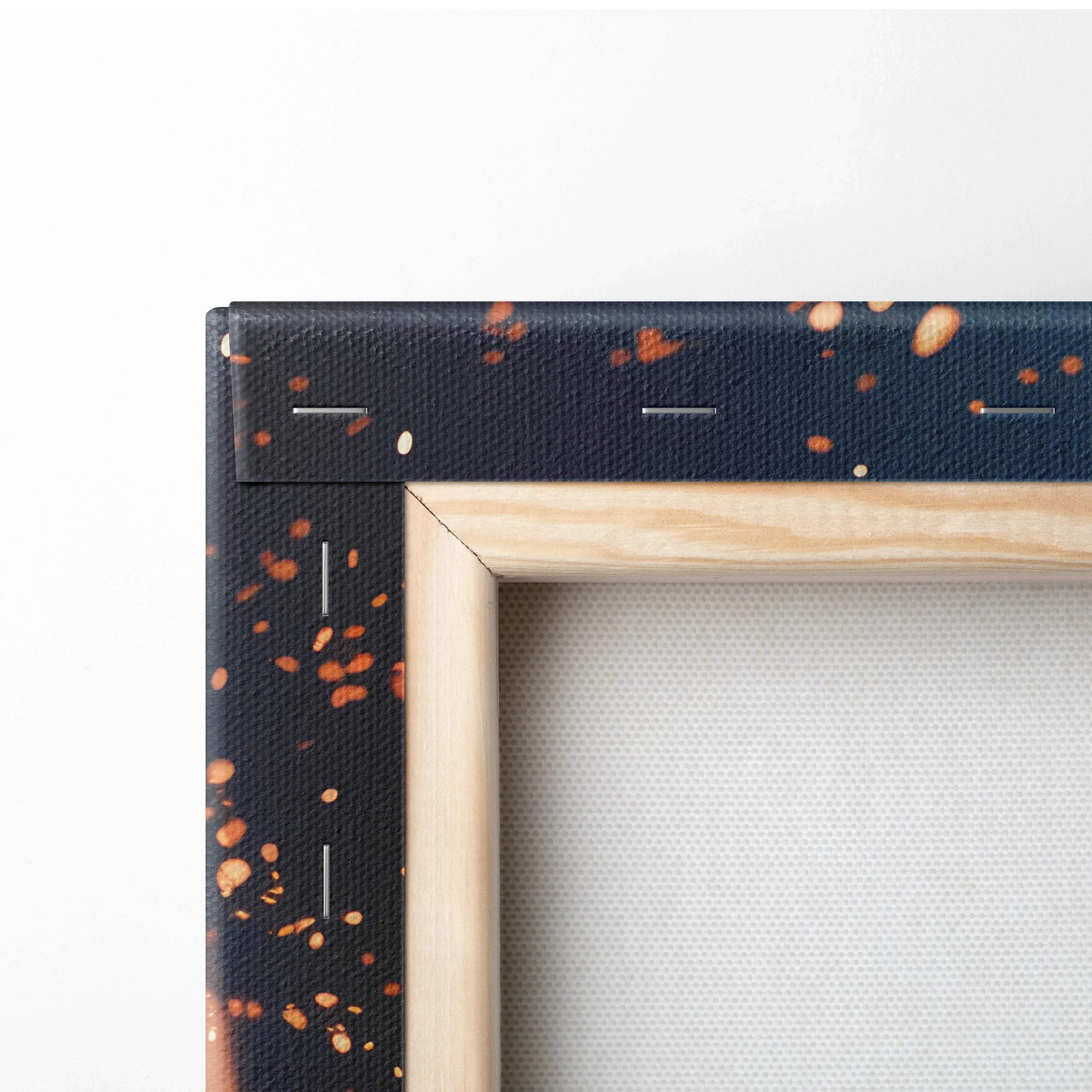Close-up of canvas corner with vibrant navy blue background and scattered orange and beige abstract splatters, natural wood.