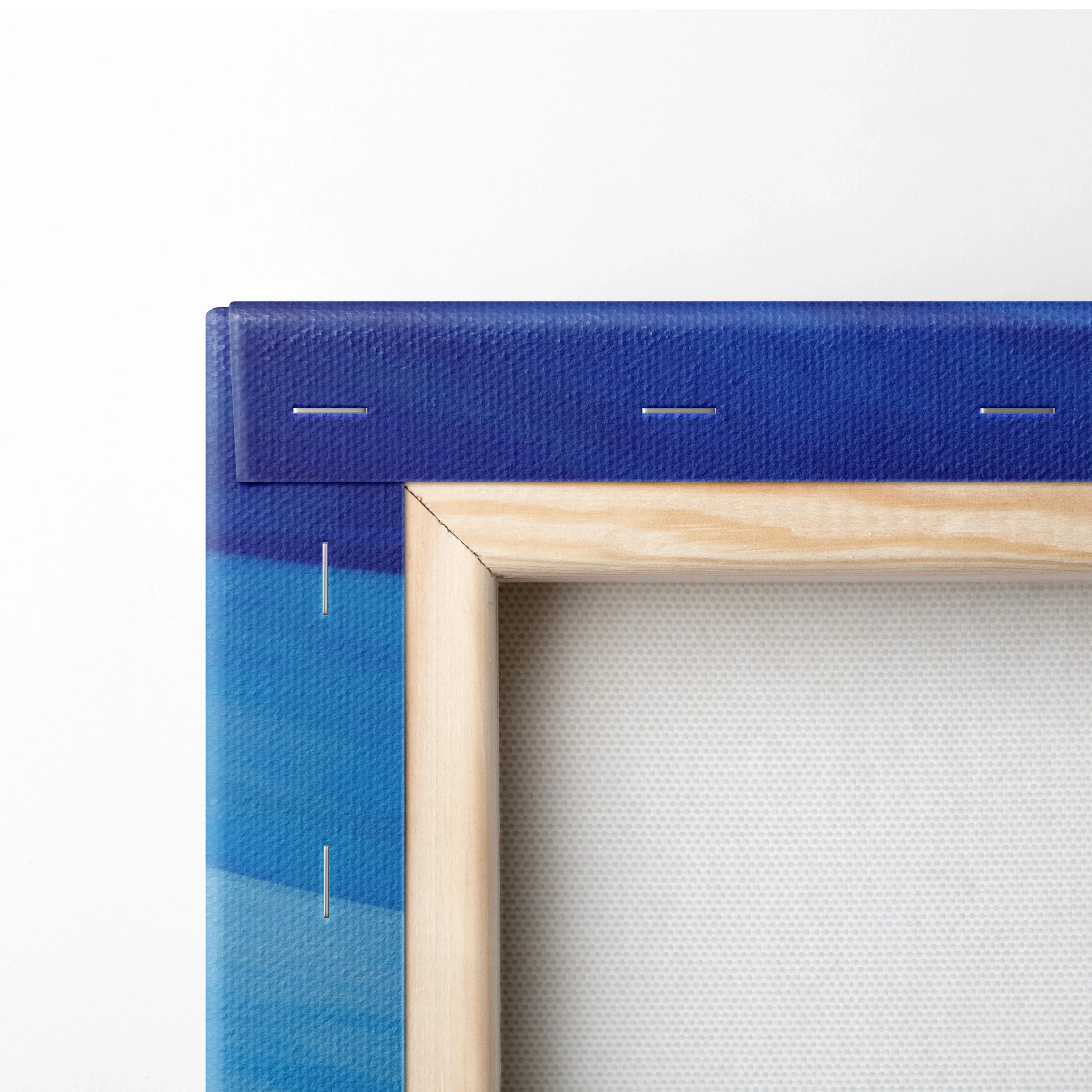 Close-up of wooden frame and blue abstract canvas art with visible staples and textured fabric backing.