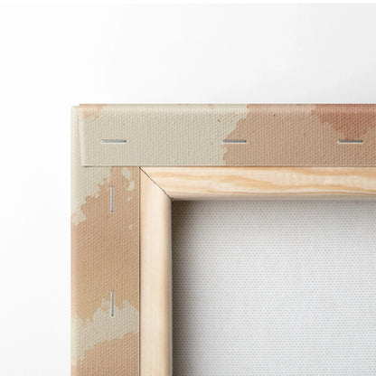 Natural wood frame corner of beige and tan watercolor canvas wall art with visible staples on back.