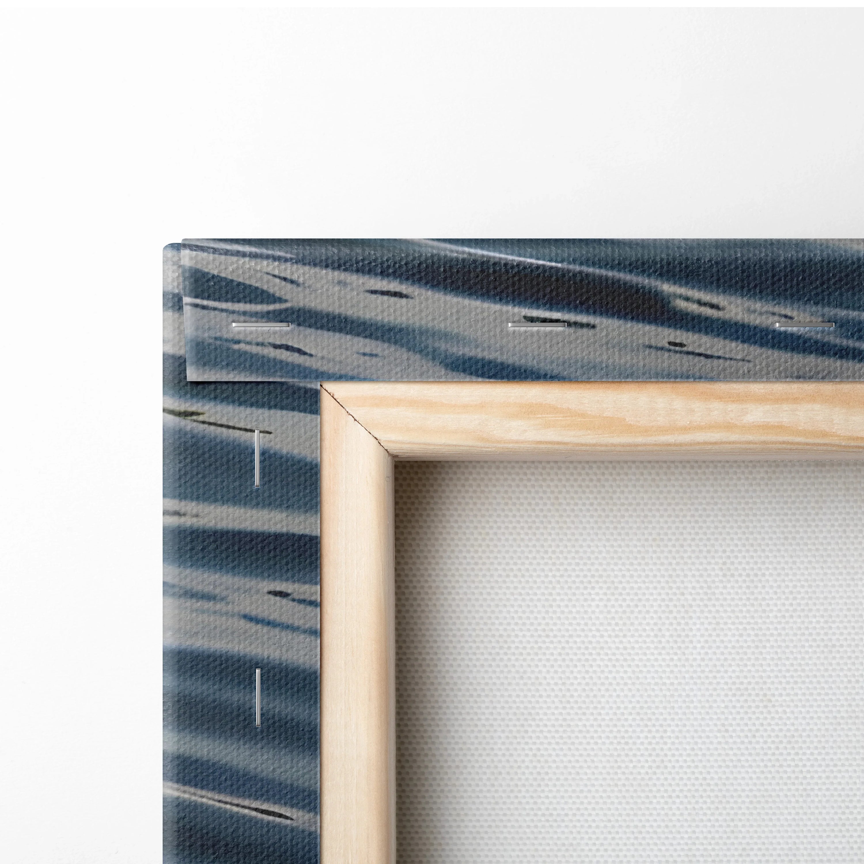 Close-up of wooden frame corner and textured canvas with blue and white watercolor ocean design wall art.