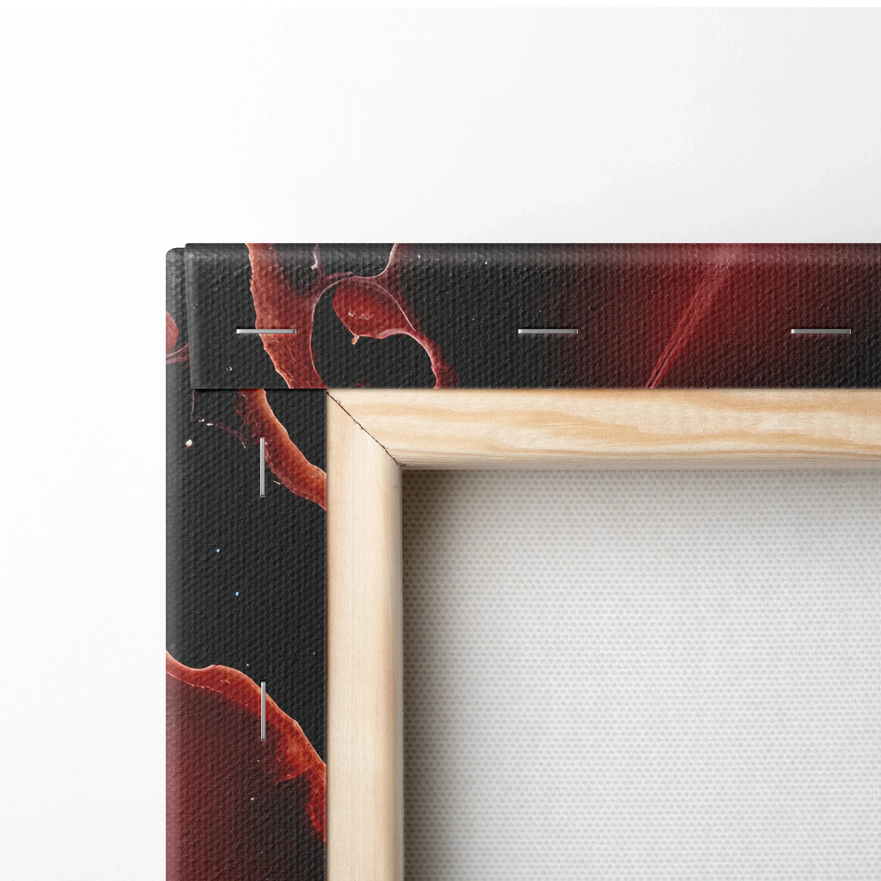 Close-up of canvas wall art corner with black background and red abstract design on wooden frame.