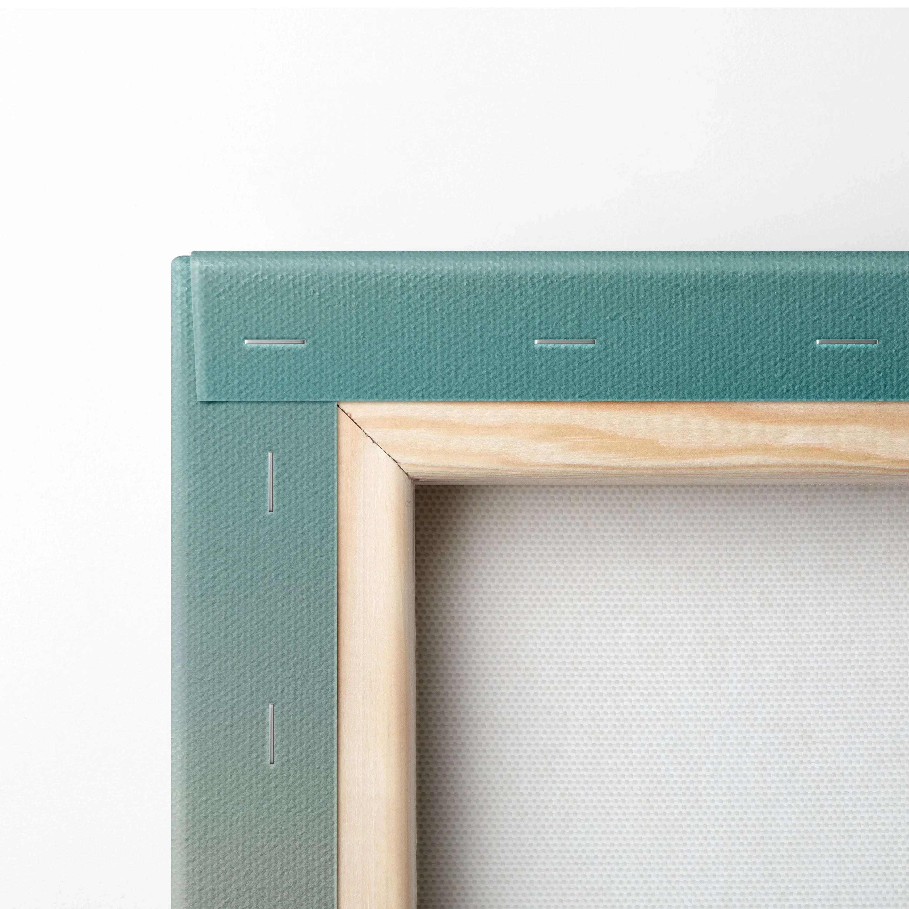 Corner detail of teal edged canvas stretched on wooden frame for wall art.