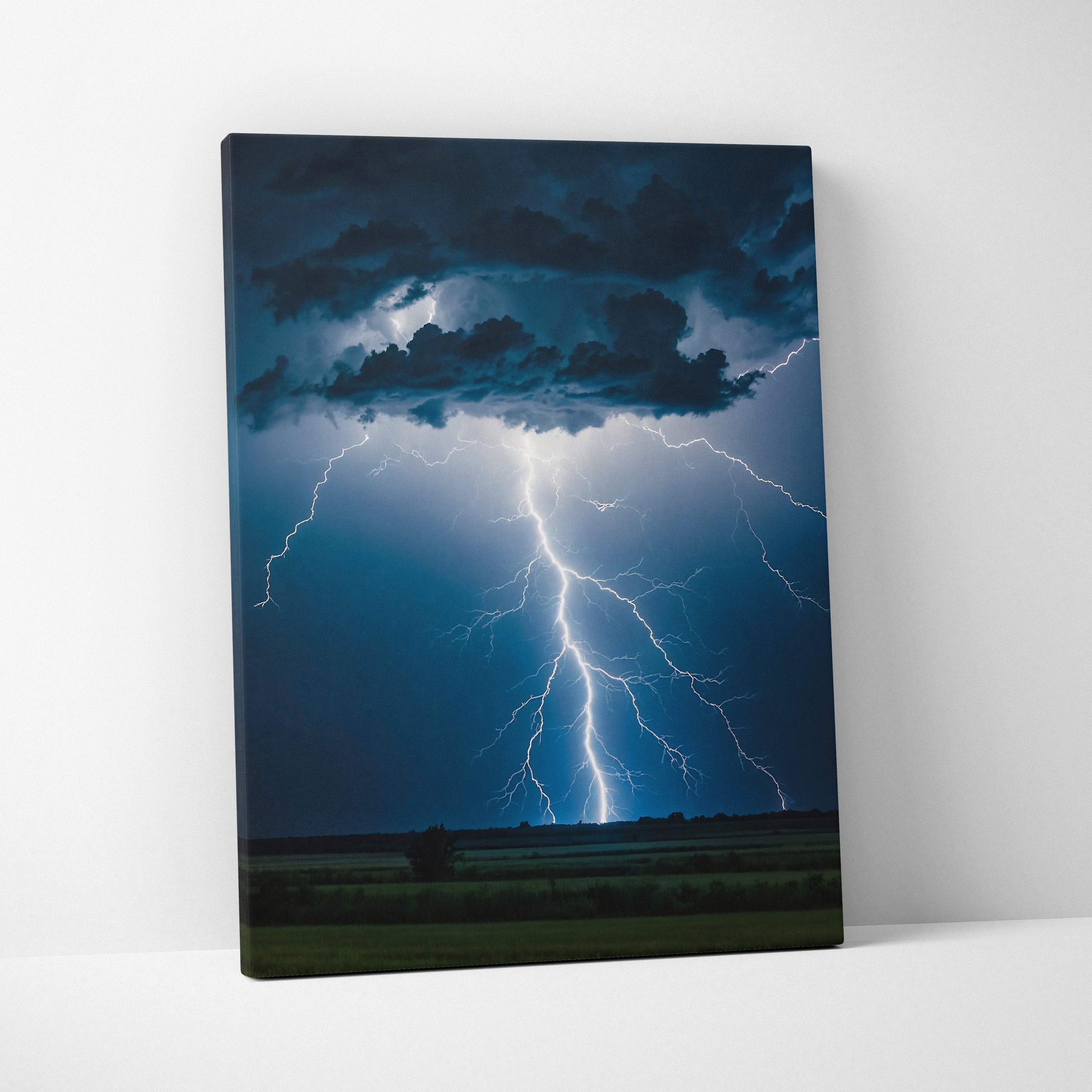 Canvas print showing a powerful cloud to ground lightning strike with deep blue and black storm clouds over fields