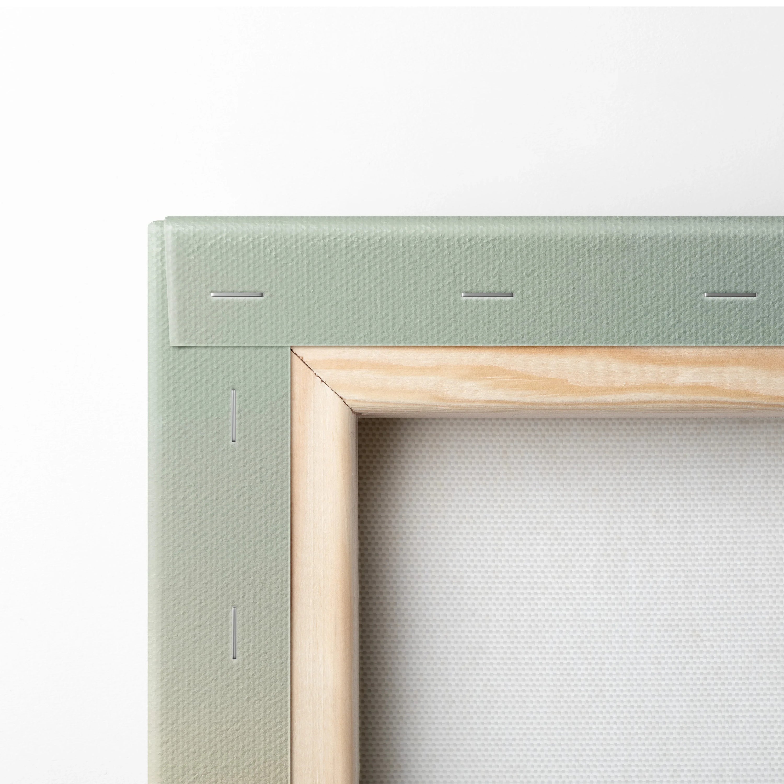 Close-up of stretched canvas corner showing wooden frame and green fabric backing for wall art.