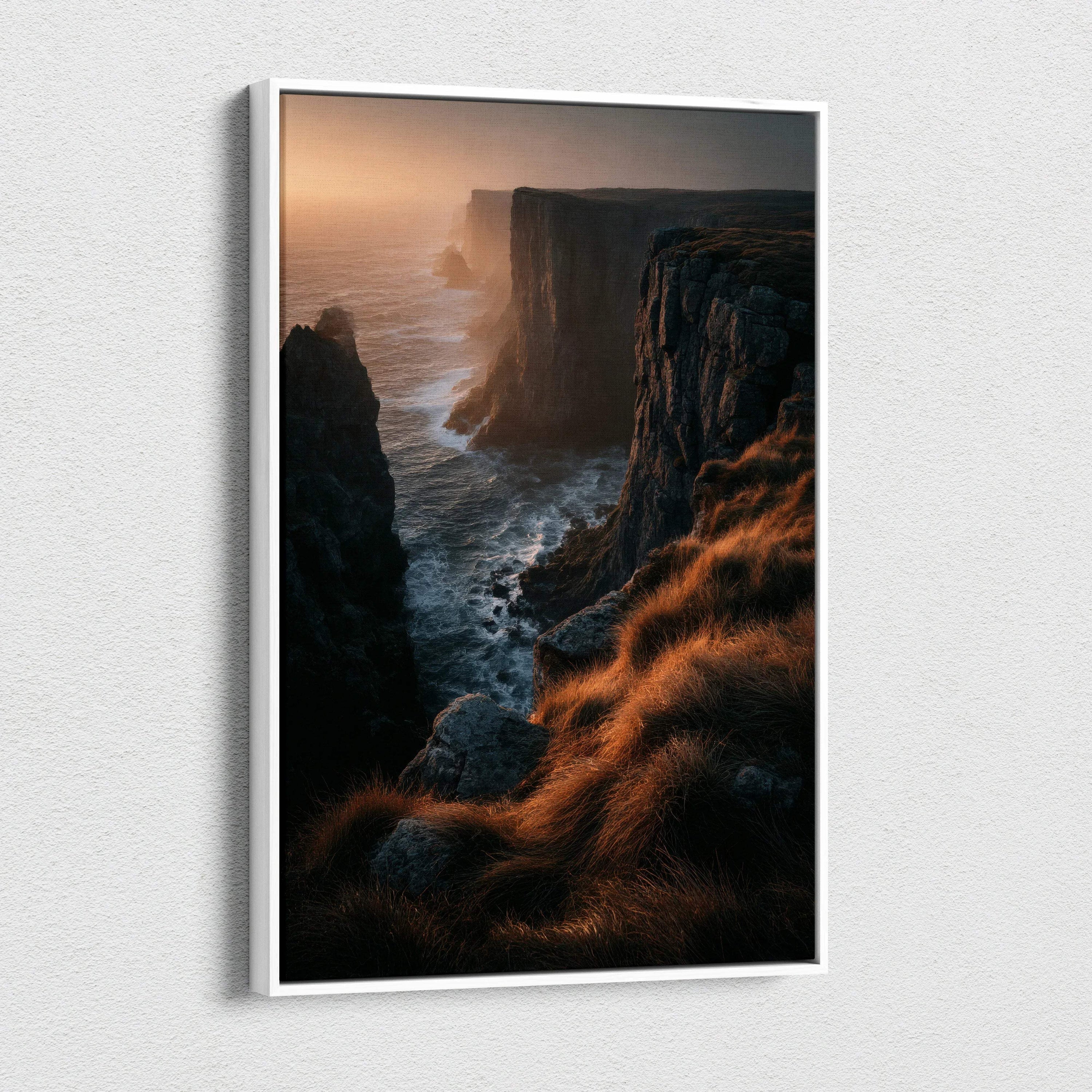 Vertical canvas wall art featuring a dramatic nature sunset over rugged cliffs with golden light on grassy foreground.