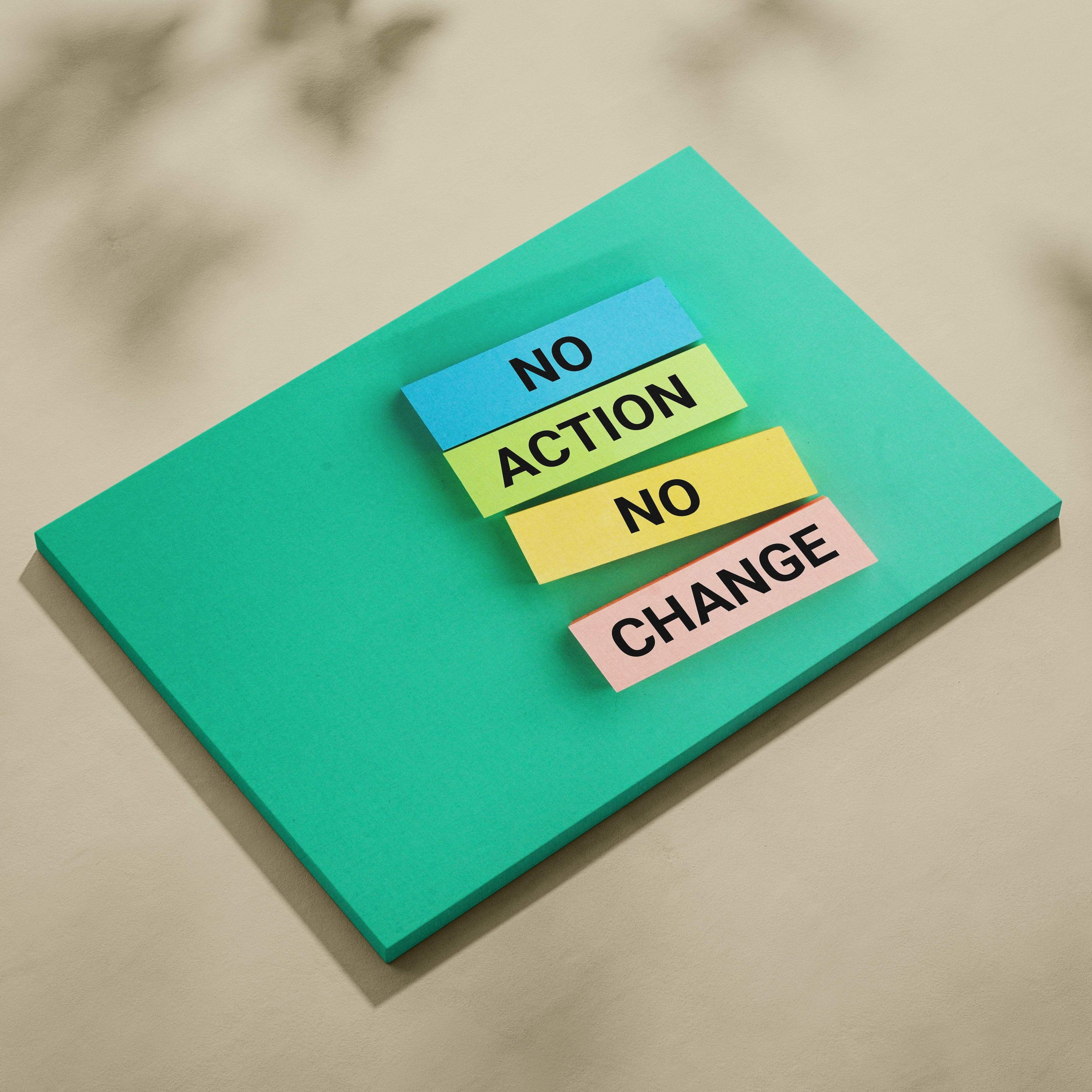 A teal sticky note pad with four colorful stacked notes displaying no action no change motivational typography print