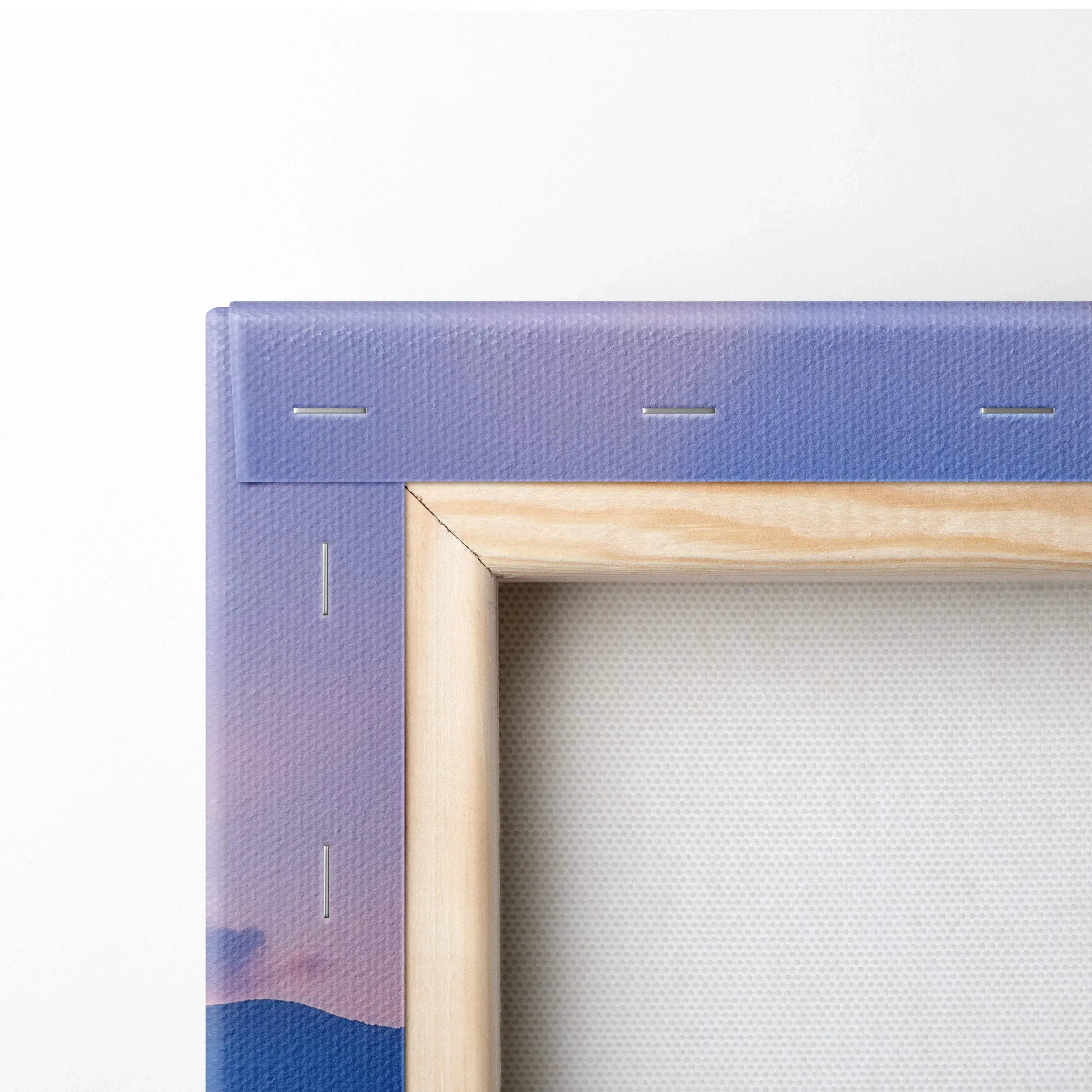 Close-up of purple sunset floral mountain canvas with natural wood frame and visible staples on wall art.