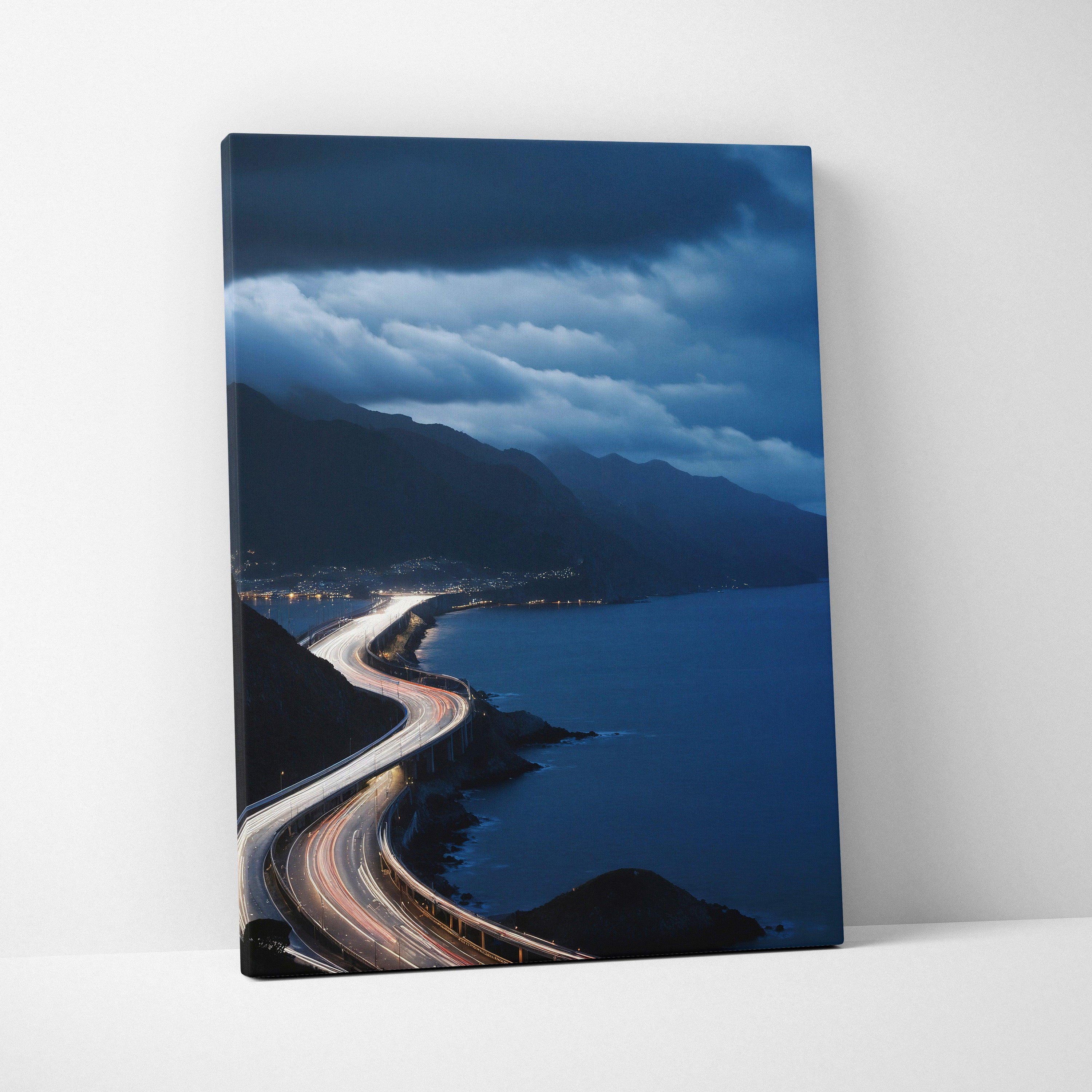 Vertical canvas wall art print featuring a winding coastal highway under a dramatic night sky with illuminated city lights.