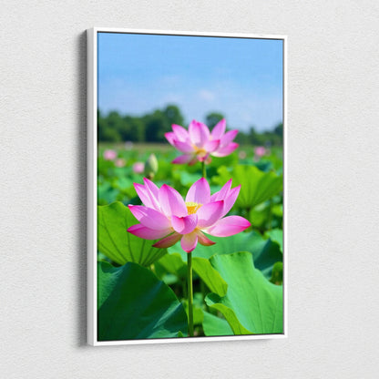 Vertical canvas wall art featuring vibrant pink lotus flowers with green leaves under clear blue sky.
