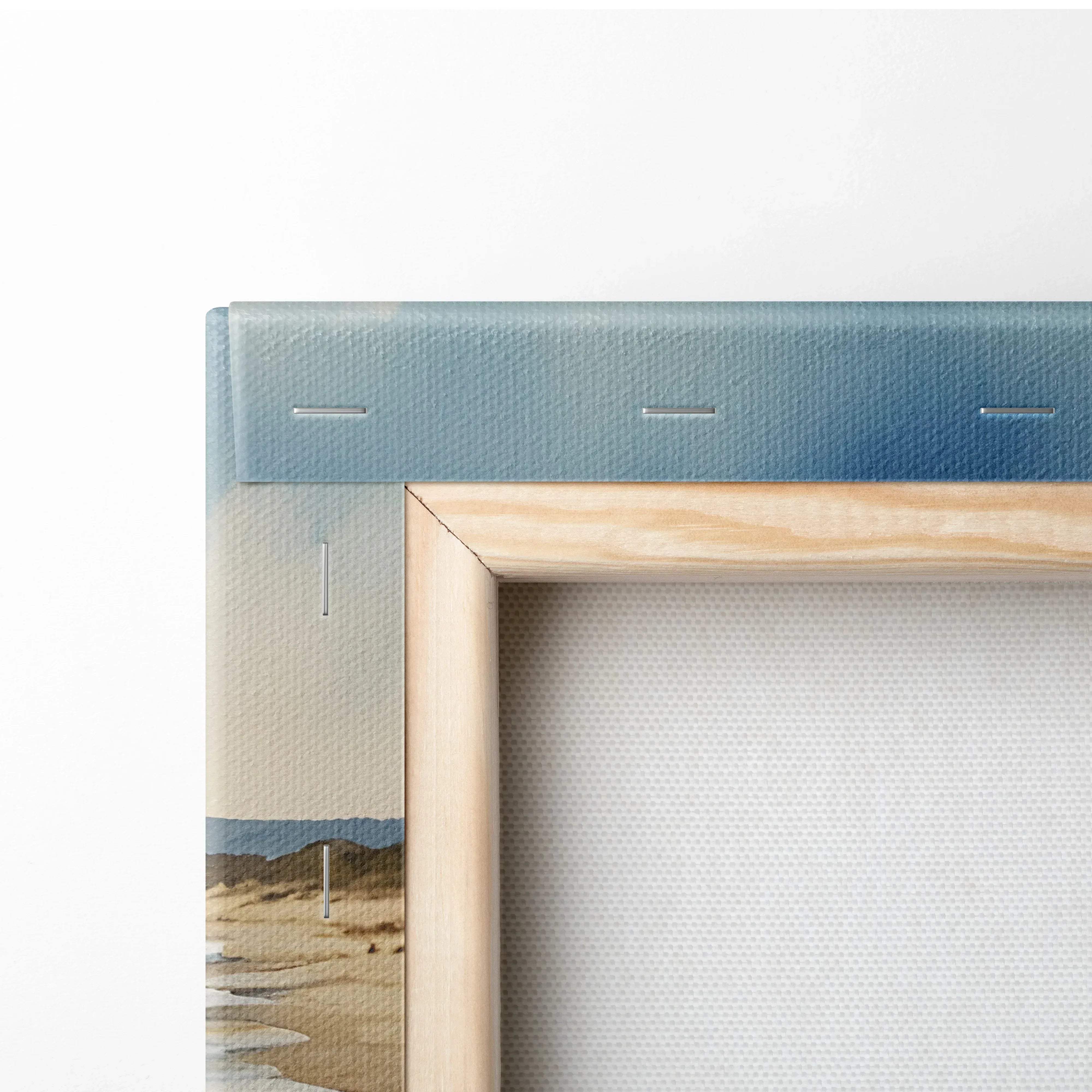 Light wood-framed canvas print of serene ocean waves over golden beach with soft blue border and textured fabric surface