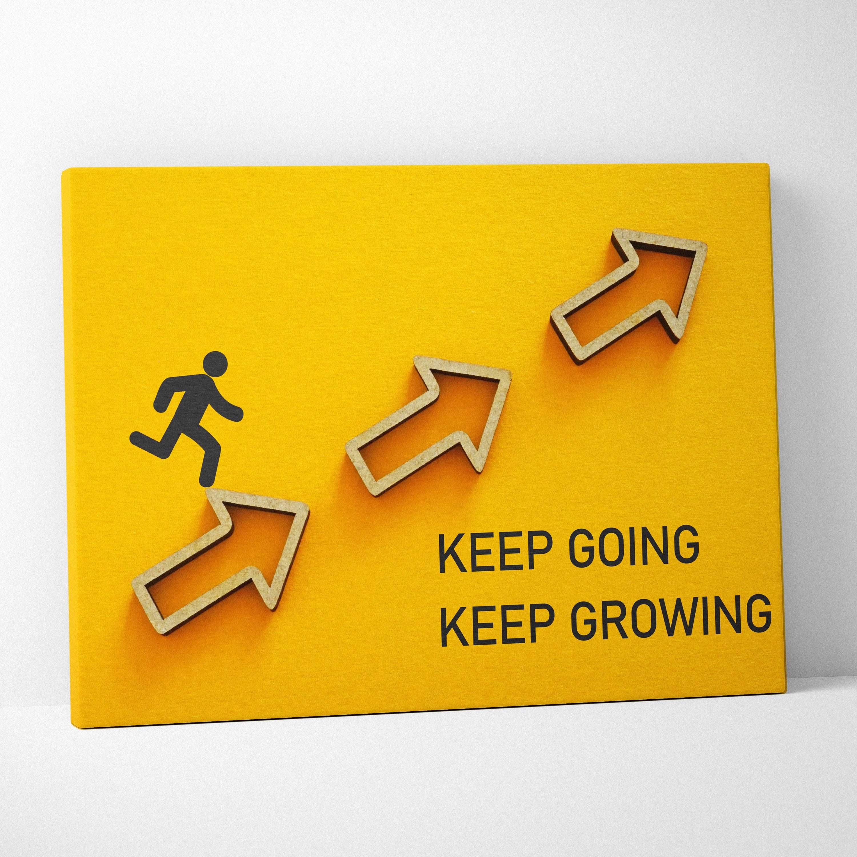 Bright yellow canvas wall art with 3D wooden arrows and a black running silhouette featuring keep going keep growing text
