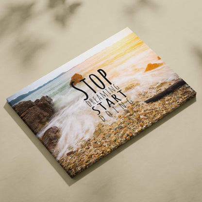Beige canvas print of coastal scene with crashing waves and pebbles featuring motivational stop dreaming start doing text