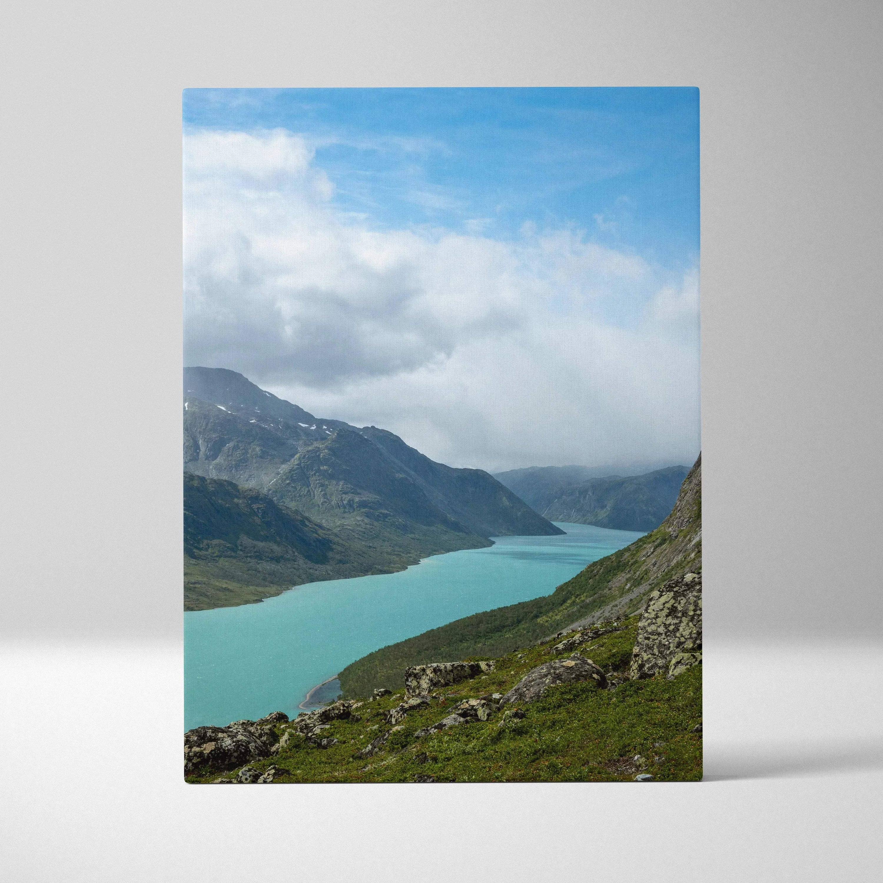 Vertical canvas wall art featuring a serene mountain landscape with a turquoise lake and cloudy blue sky.