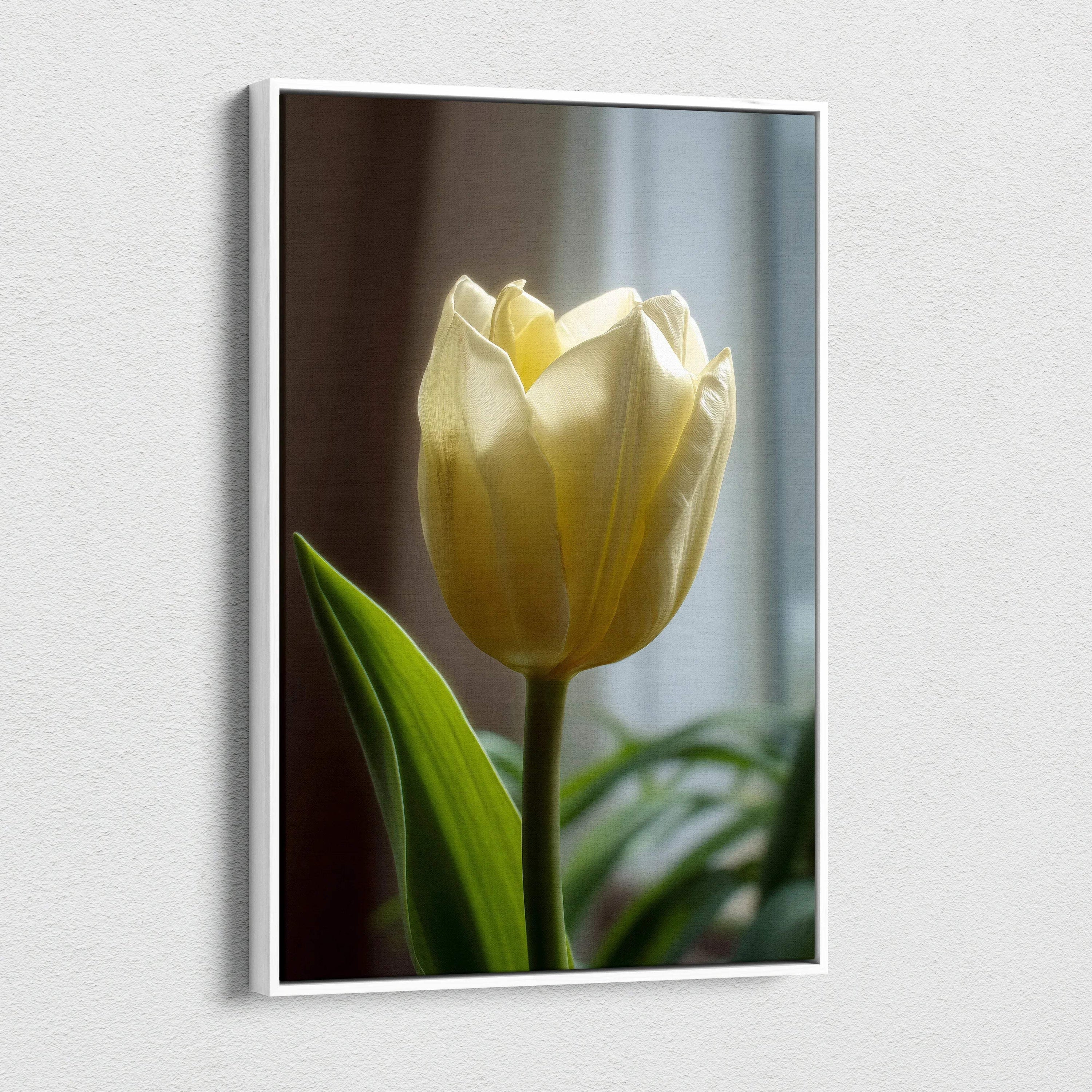 Vertical canvas wall art featuring a close-up of a single pale yellow tulip with green leaves against a blurred background.