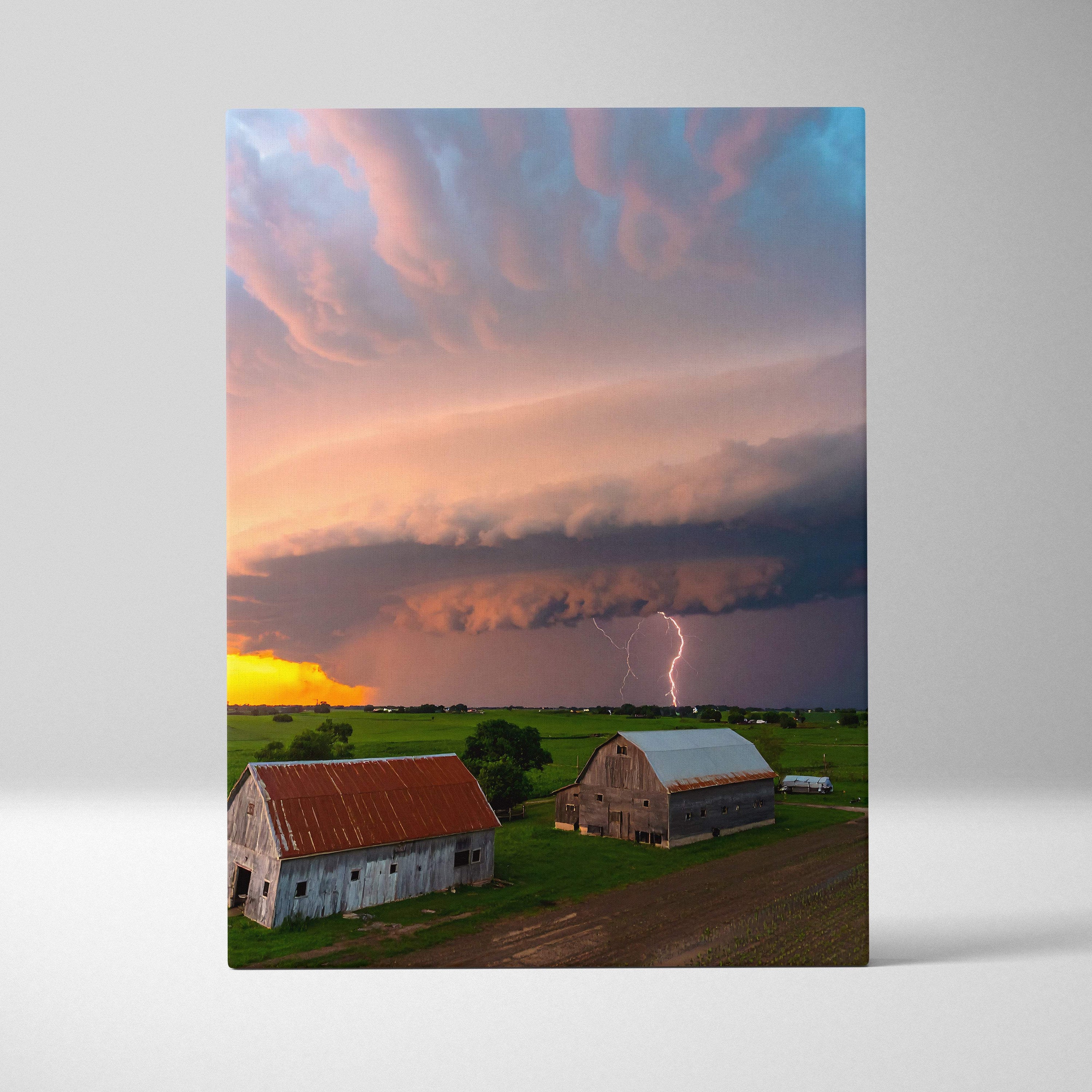 Rectangular canvas print of two rustic barns under lightning and colorful clouds for rustic home decor wall art