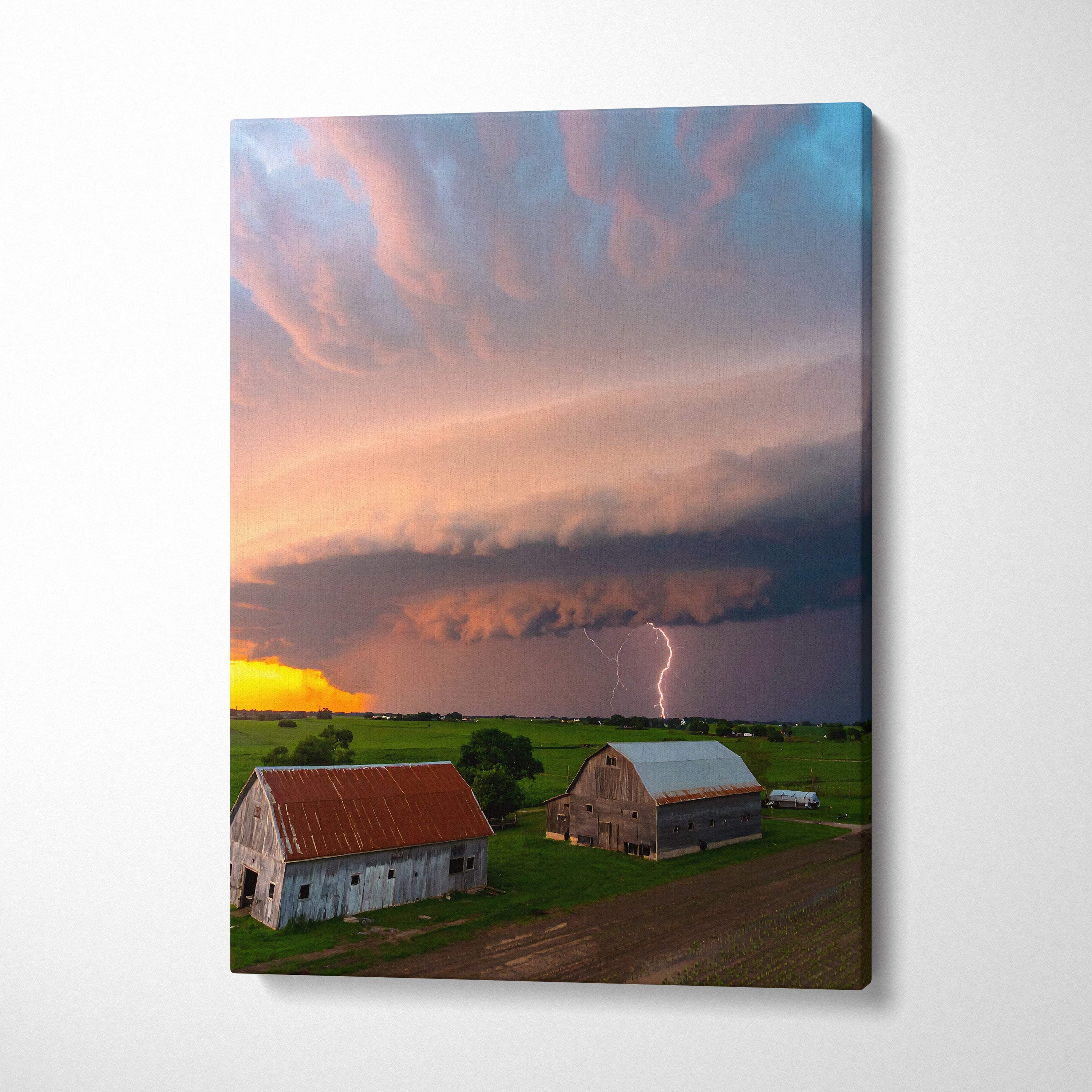 Canvas print of a dramatic lightning storm over rural barns with vibrant pink orange and blue clouds for rustic decor