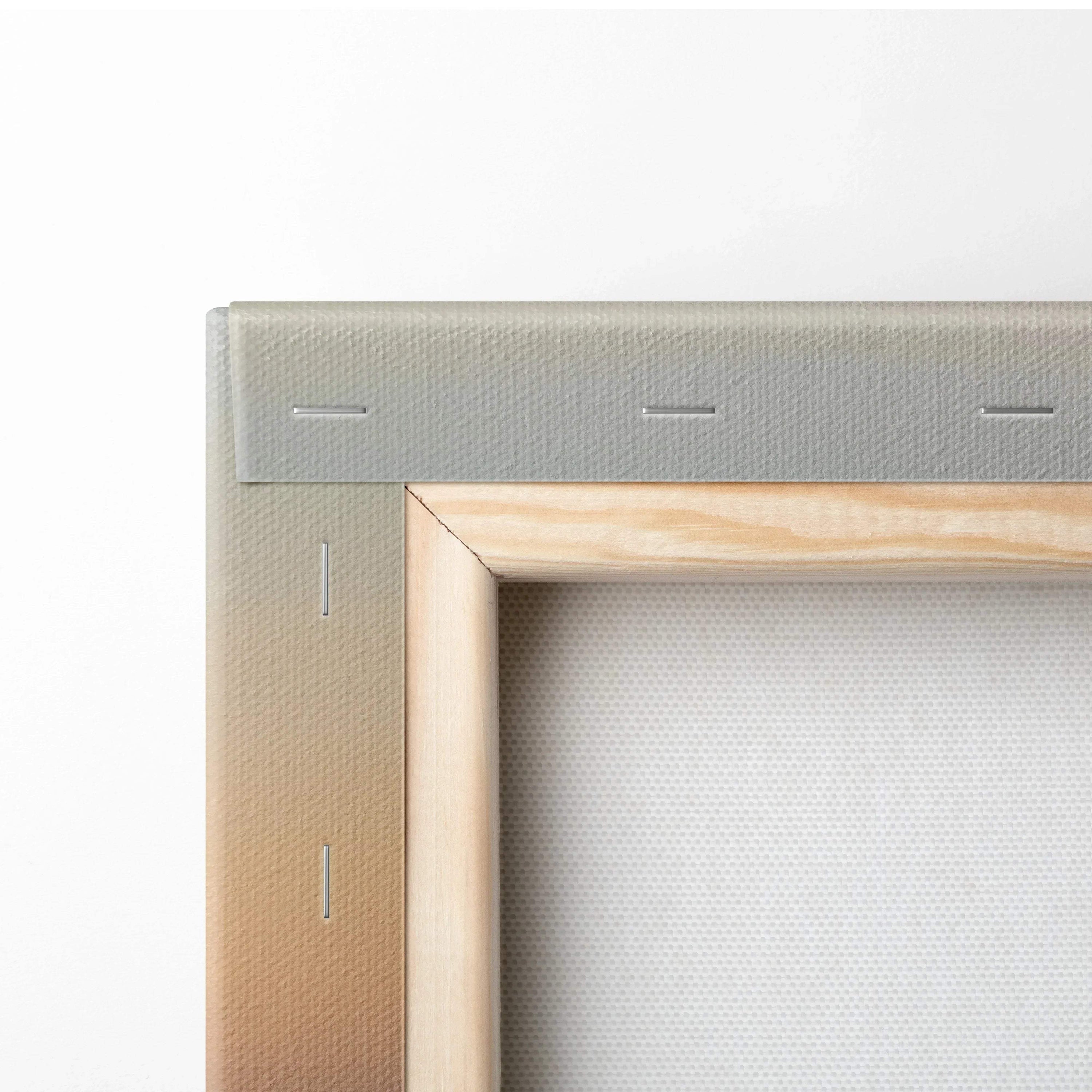 Close-up of wooden frame and stretched canvas corner with visible staples on wall art print.