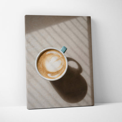 Canvas wall art featuring a top-down view of a latte in a blue cup casting a shadow on a textured surface.