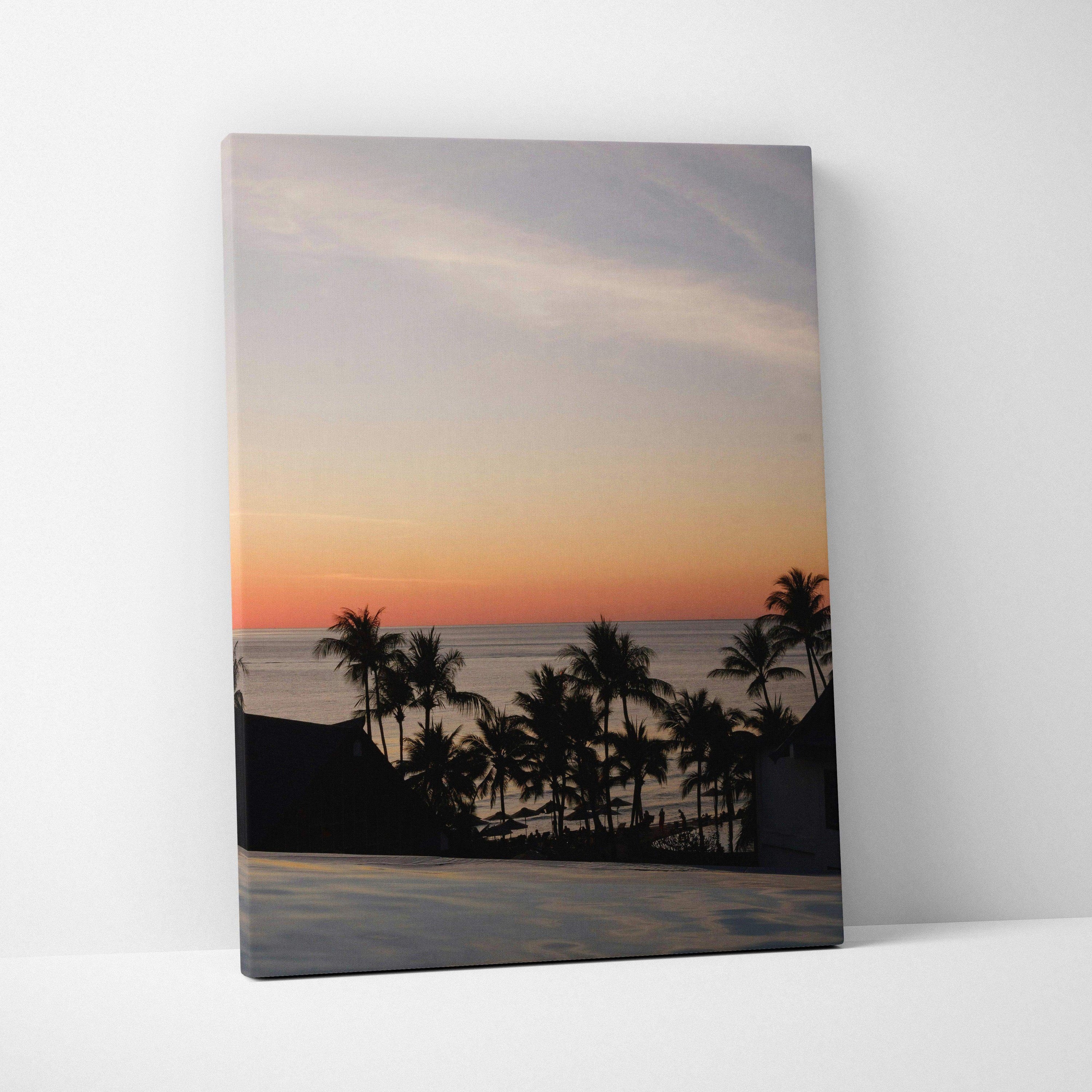 Canvas wall art featuring a vivid golden sunset over a beach with silhouetted palm trees and calm ocean.
