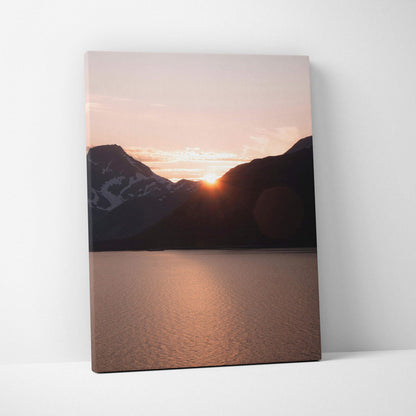Canvas wall art featuring a mountain silhouette with a glowing sunset over calm water.