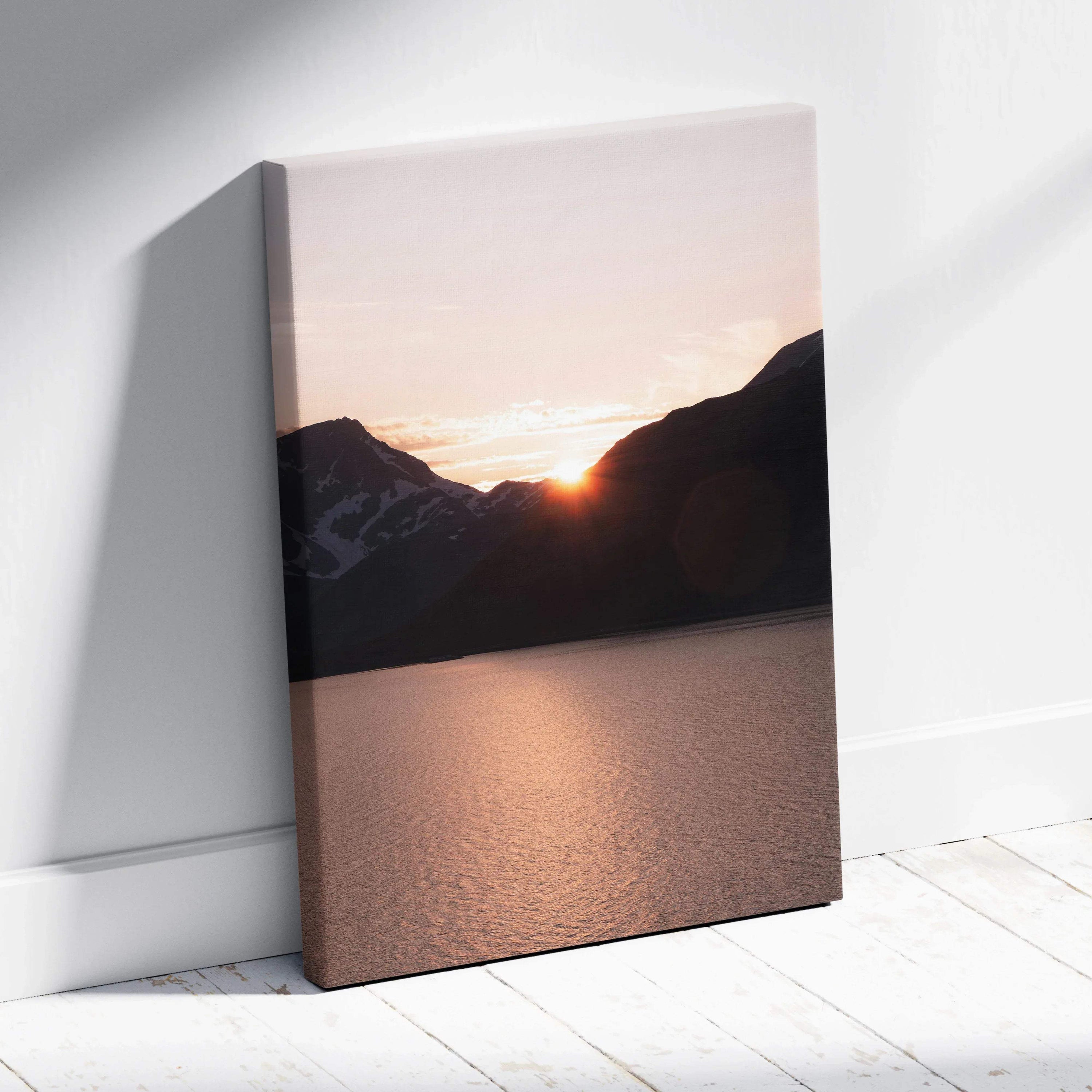 Vertical canvas wall art featuring a sunset over dark mountain silhouettes above a calm lake surface.