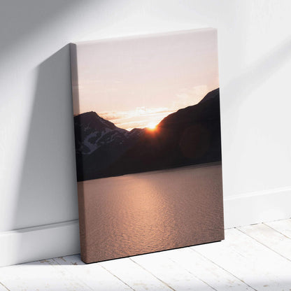 Vertical canvas wall art featuring a sunset over dark mountain silhouettes above a calm lake surface.