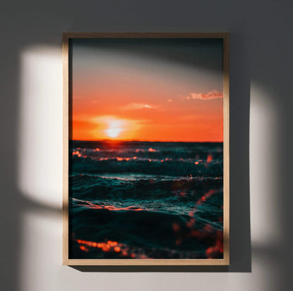 Vertical ocean sunset wall art poster with vibrant orange sky and dark waves in wooden frame.