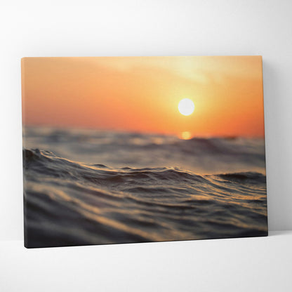Sunset over ocean waves canvas wall art with warm orange and yellow tones.