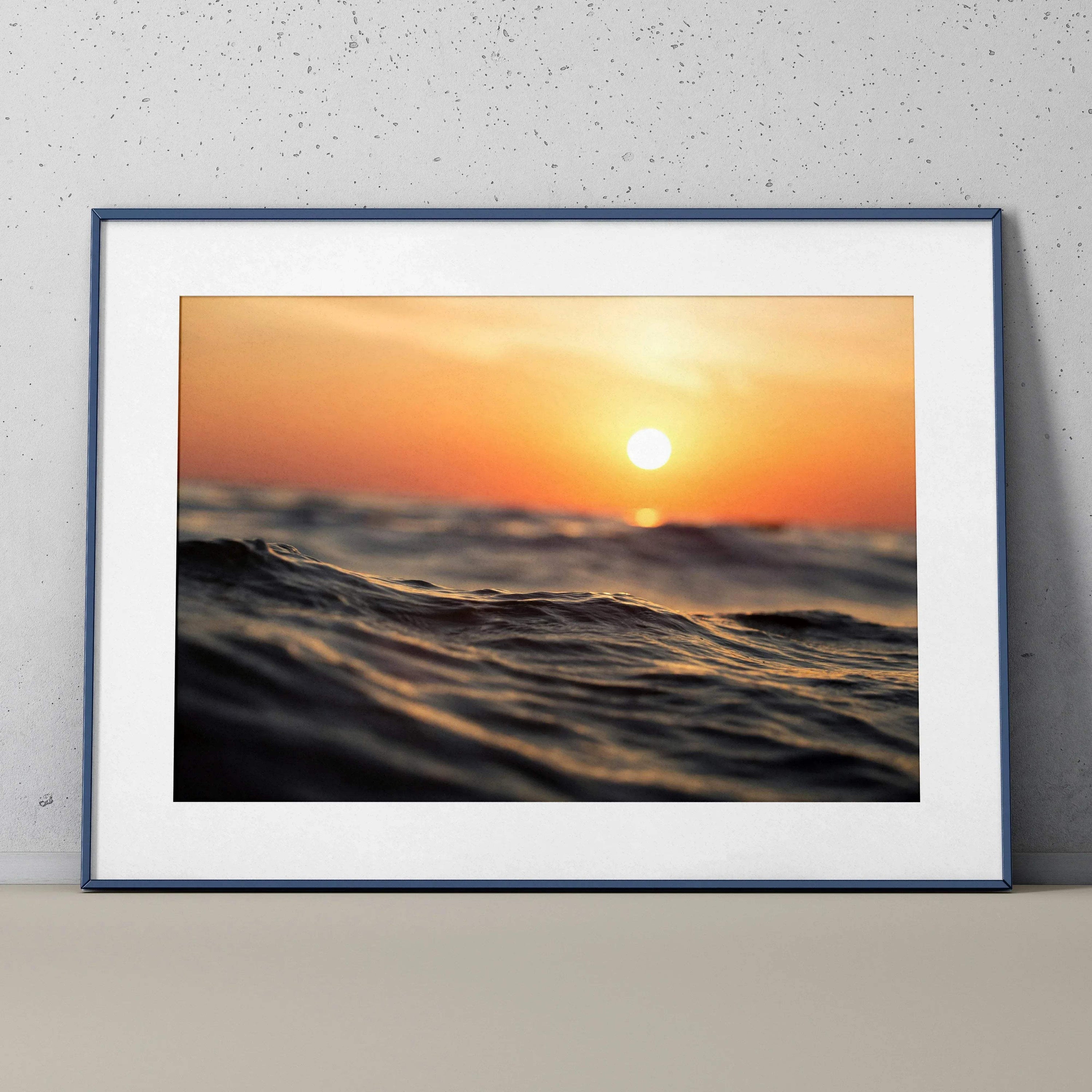Serene ocean sunset poster wall art with warm orange and blue tones in a black frame.