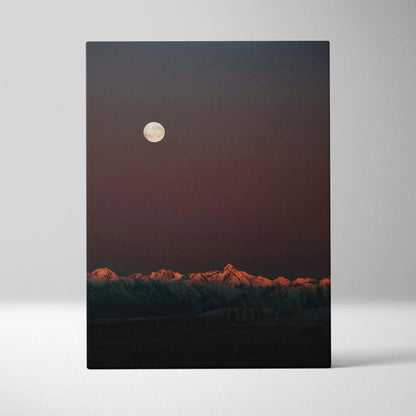 Canvas wall art featuring a glowing full moon above a mountain range at dusk with warm light on the peaks.