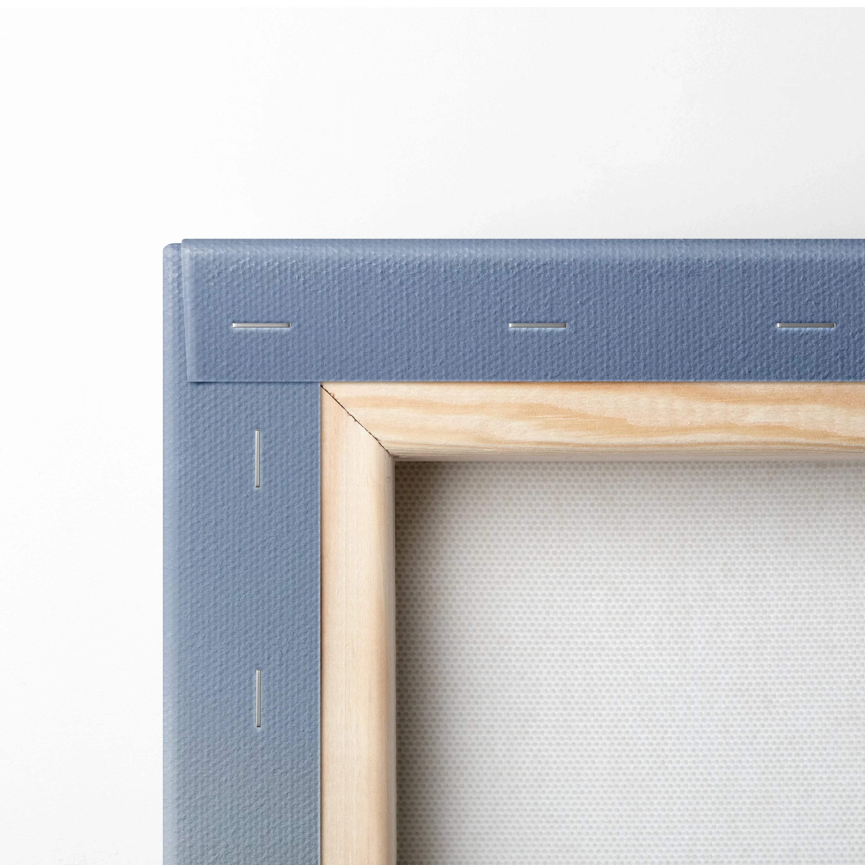 Close-up of wooden frame corner on stretched canvas wall art with blue fabric backing.