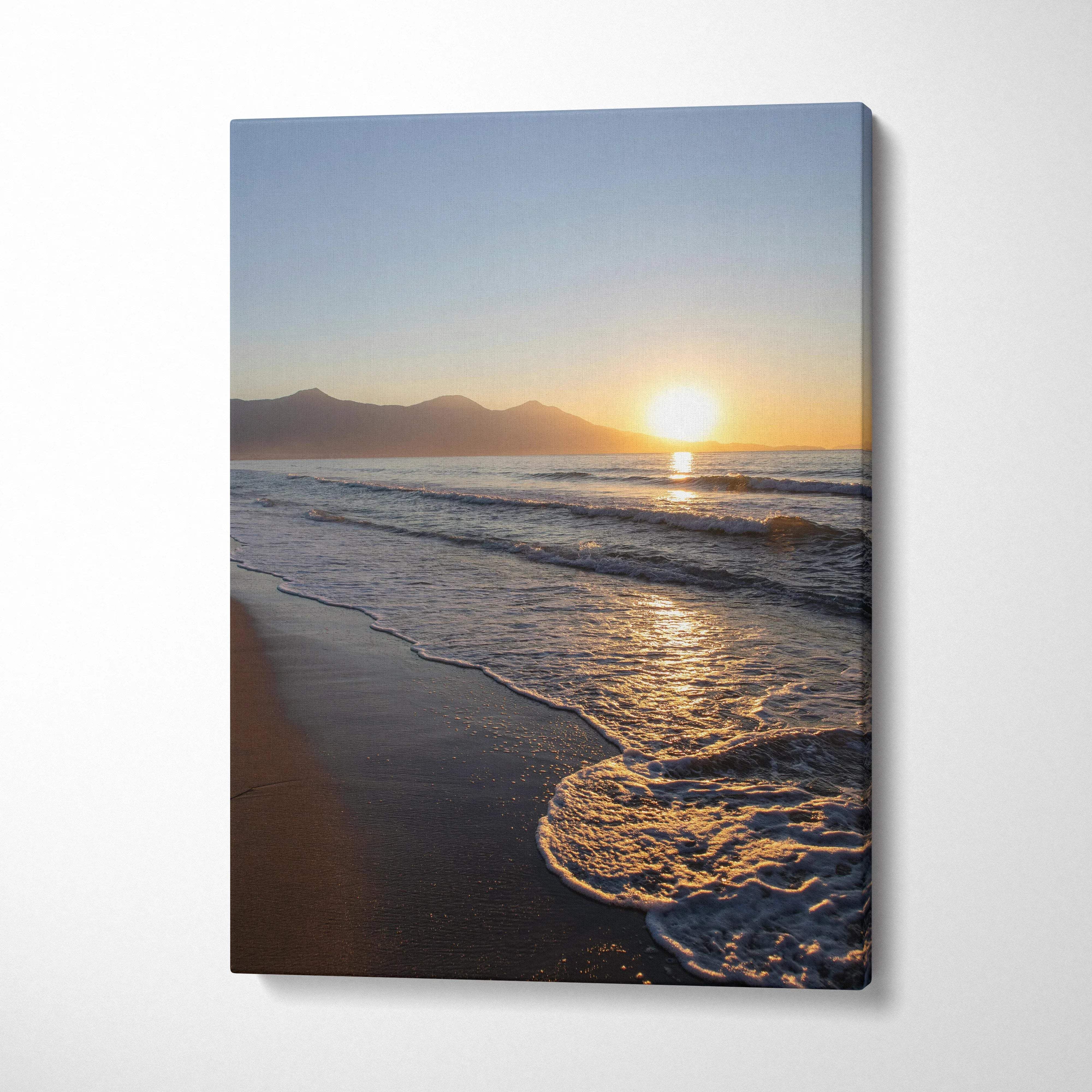 Canvas wall art of a serene beach at sunset with gentle ocean waves and distant mountains.