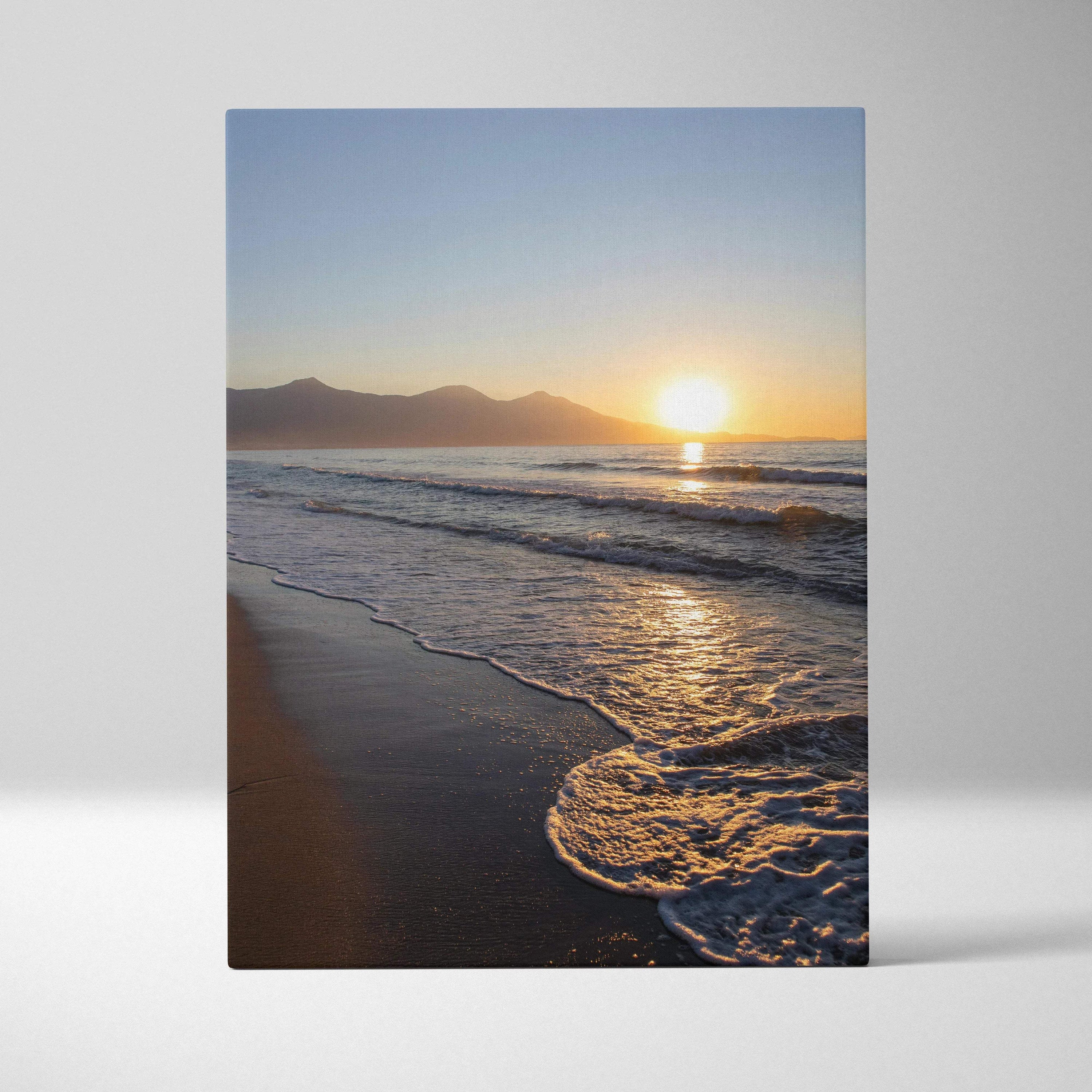 Canvas wall art of a serene sunset over ocean waves with silhouetted mountains in the background.