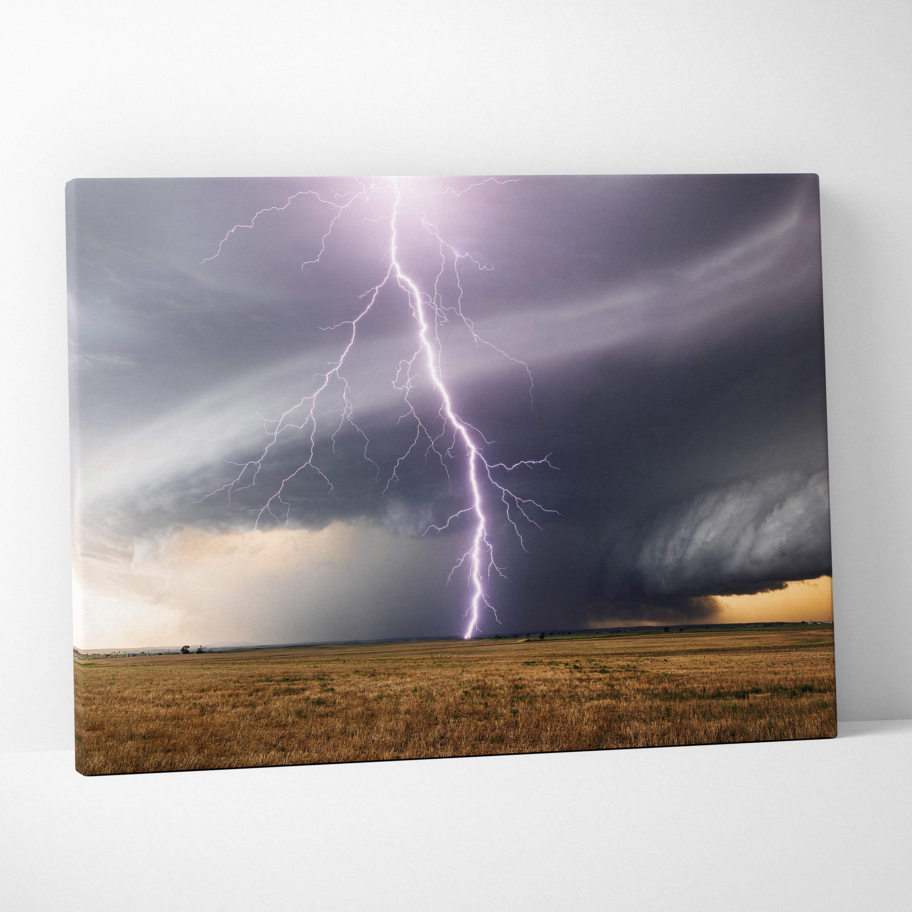Canvas print of a dramatic lightning strike over a golden field with purple bolt and dark rotating storm clouds