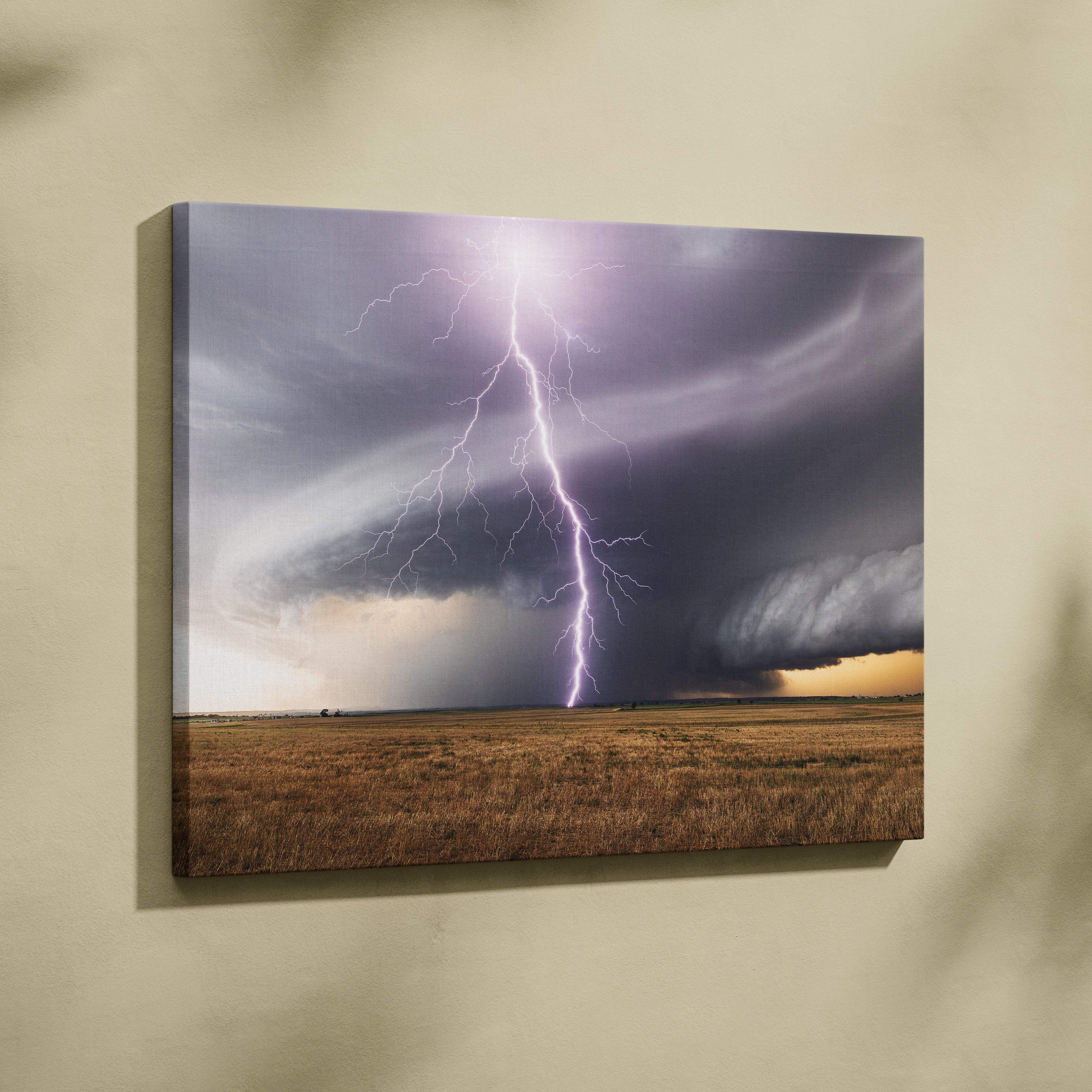 Canvas print of a dramatic lightning strike with purple and white bolts over dark storm clouds and golden brown grassland