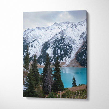 Vertical canvas wall art featuring snow-capped mountain peaks above a turquoise lake with evergreen trees.
